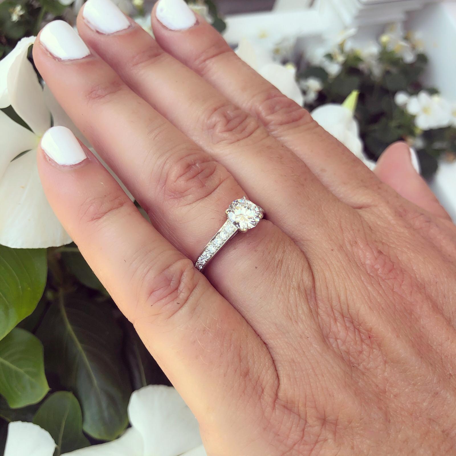 ¡Belleza clásica en estado puro! Un brillante diamante talla brillante redondo de 1,06 quilates con graduación GIA D/VS2 es la pieza central de este magnífico anillo de platino. El anillo presenta otros 18 diamantes con un peso total de 0,38