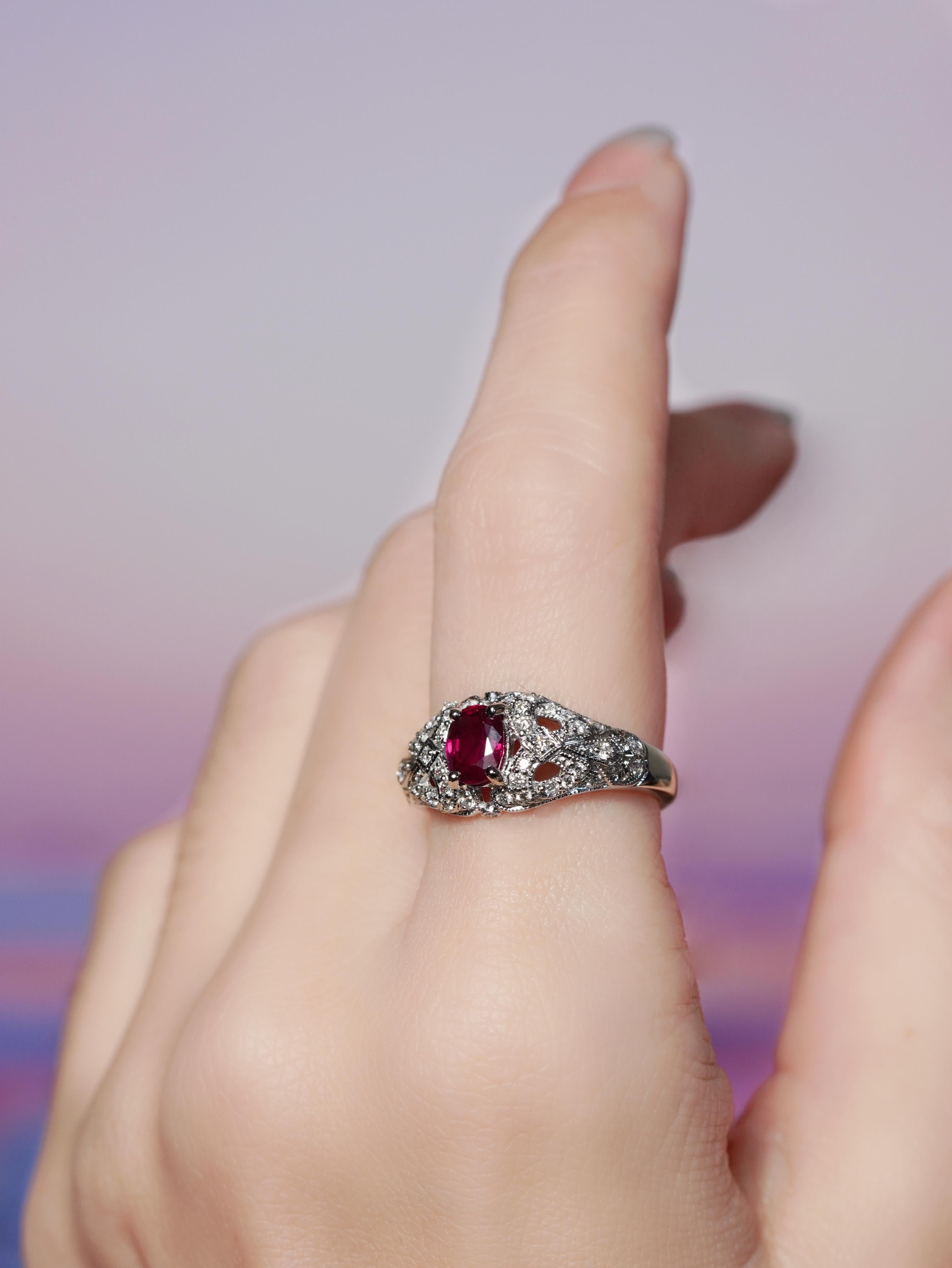 Make a bold statement with this contemporary style engagement ring. At its heart sits a vivid oval ruby, prong-set to showcase its rich hue. The diamond-adorned shoulders draw inspiration from graceful floral patterns, blending vintage elegance with