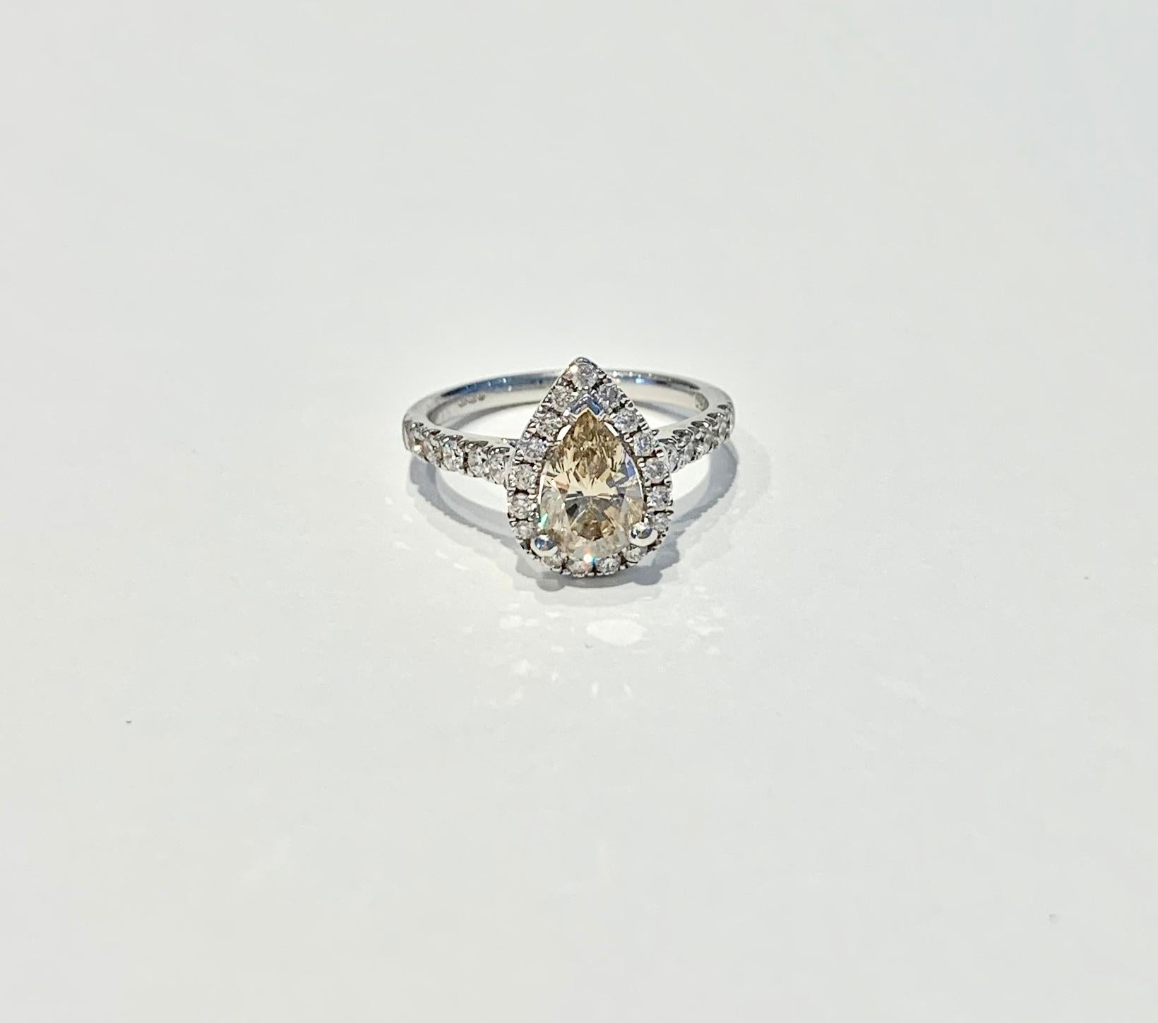 GIA Certified 1.07ct Fancy Brown/Yellow* Pear Cut diamond, set in a diamond halo design in 18ct White Gold.  There is amazing scintillation from both the Pear Cut diamond and the diamonds in the Halo and band.  This ring could make a unique