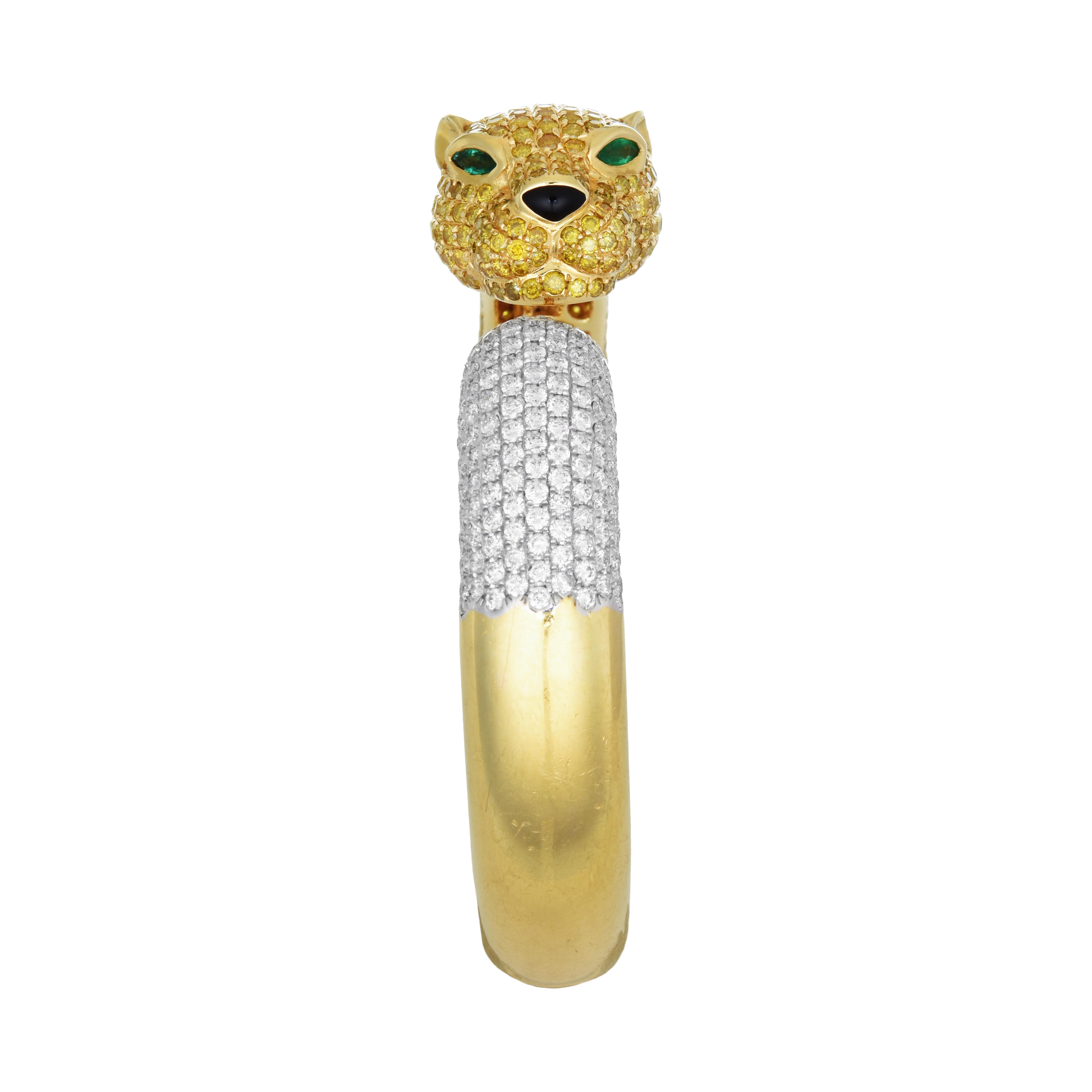 This beautifully striking bangle is crafted to resemble a panther. Its head section features pave set yellow diamonds, with eyes made of emeralds. Its tail section features pave set white diamonds set in white gold. The bangle itself is made of