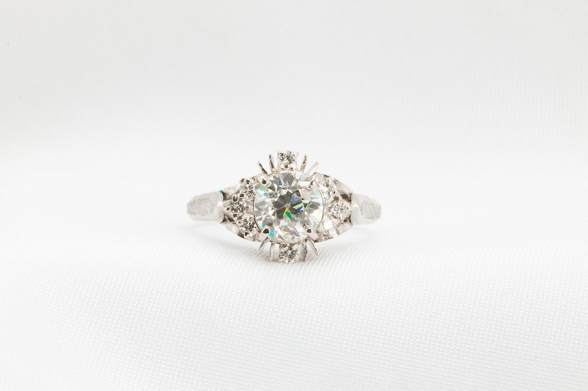 Dieser Vintage-Verlobungsring aus den 1940er Jahren ist aus Platin 850 gefertigt und hat ein geschätztes Gesamtgewicht von 1,35 Karat. In seinem Zentrum befindet sich ein atemberaubender 1,15-Karat-Diamant im alten europäischen Schliff, der vom GIA