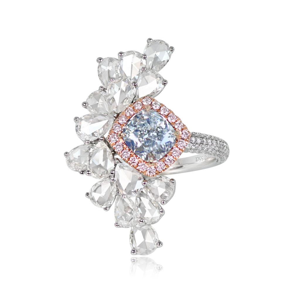 This captivating ring showcases a 1.18-carat GIA-certified cushion-cut Fancy Very Light Blue diamond, elegantly set in prongs and encircled by a halo of round fancy pink diamonds weighing 0.16 carats. The design is asymmetrical, featuring