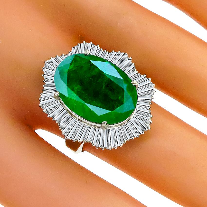 This stunning platinum ballerina ring is centered with a lovely GIA certified oval cut Zambian emerald that weighs 11.89ct. The enhanced clarity of this emerald is F2. The center stone is accentuated by dazzling baguette cut diamonds that weigh