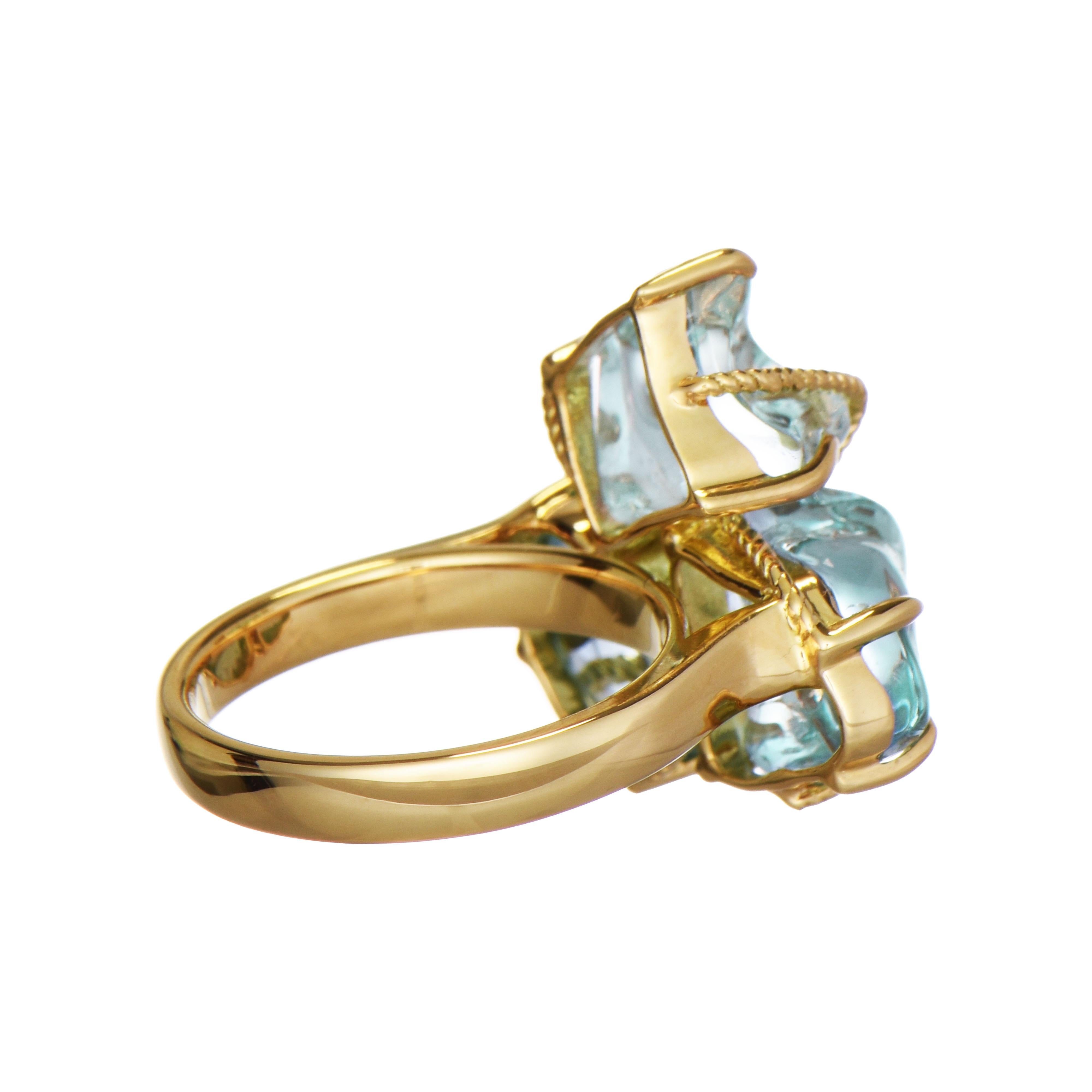 This eye-catching three-stone cocktail ring showcases tumbled aquamarine gemstones, artistically set in yellow gold. The three irregularly shaped stones are enclosed by a twisted, rope-like yellow gold design.

3 Aquamarine Gemstones: 11.89 Carats,