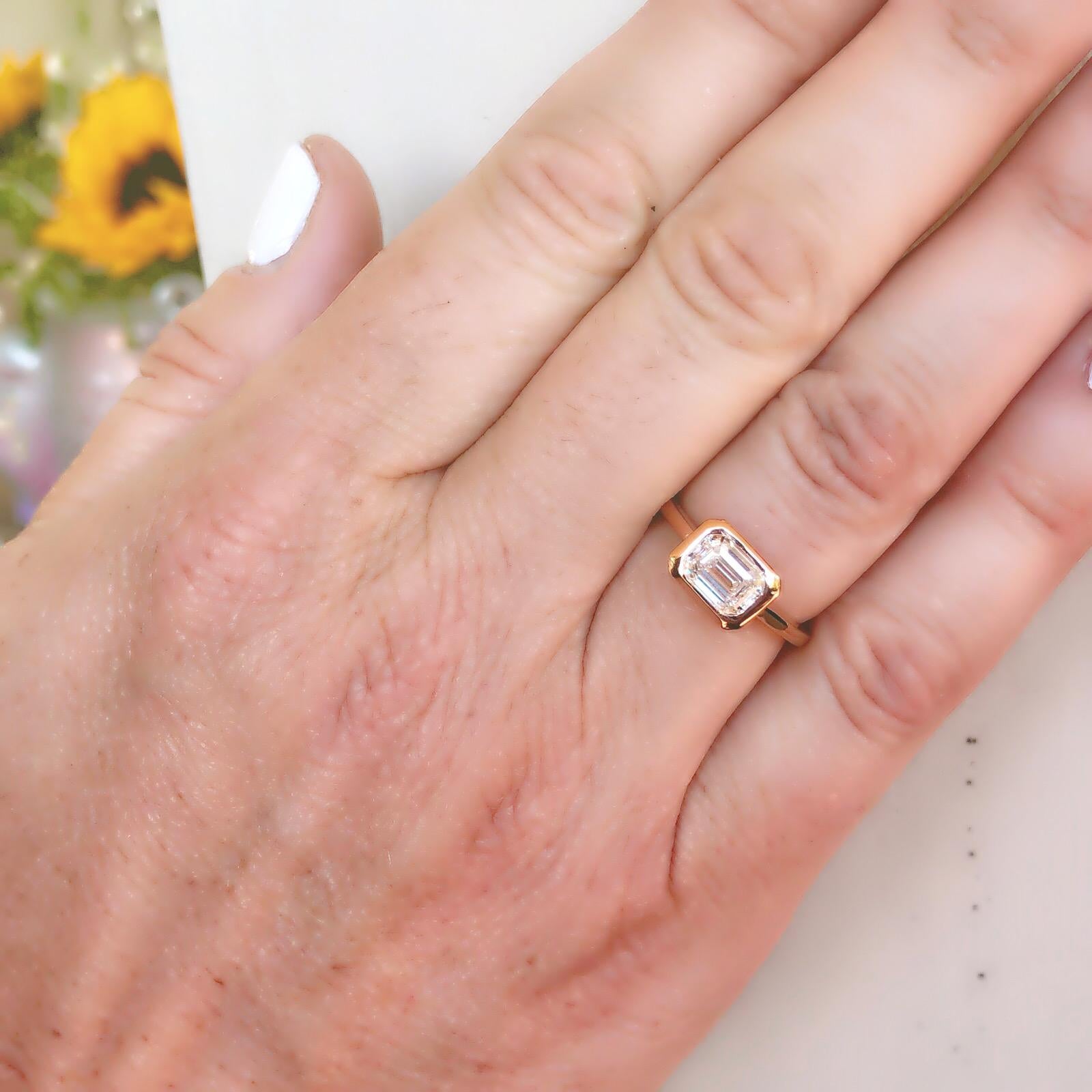 Classic yet with a modern twist, this 18k rose gold solitaire ring appeals to contemporary tastes! Featuring a GIA emerald-cut diamond, I color and VS1 clarity, with beautiful flash, excellent to very good attributes, and bezel-set in horizontal