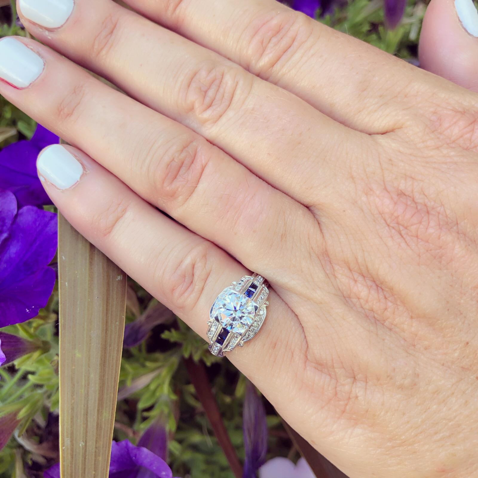Centelleante y elegante, este anillo de compromiso de platino de inspiración vintage presenta un brillante diamante redondo talla brillante GIA de 1,26 quilates G/VVS2, con zafiro talla cuadrada y acentos de diamante redondo talla brillante, para un