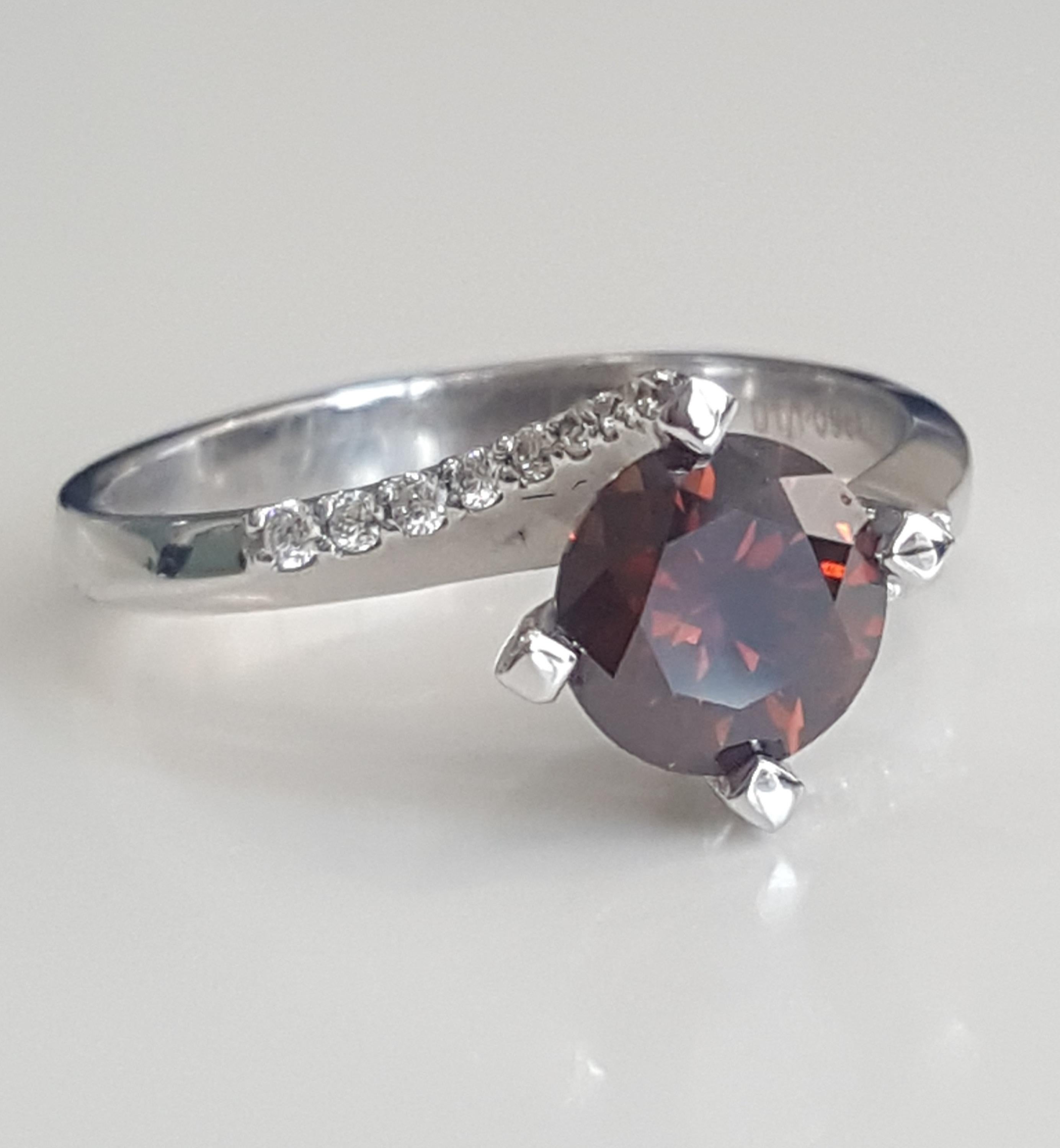 This crisp, elegant and polished ring is elegantly designed and custom made by Moguldiam Inc in 18 k white gold. Centering a GIA certified natural fancy dark orange brown weighing 1.09 carat with VS1 clarity and white small round brilliant diamonds