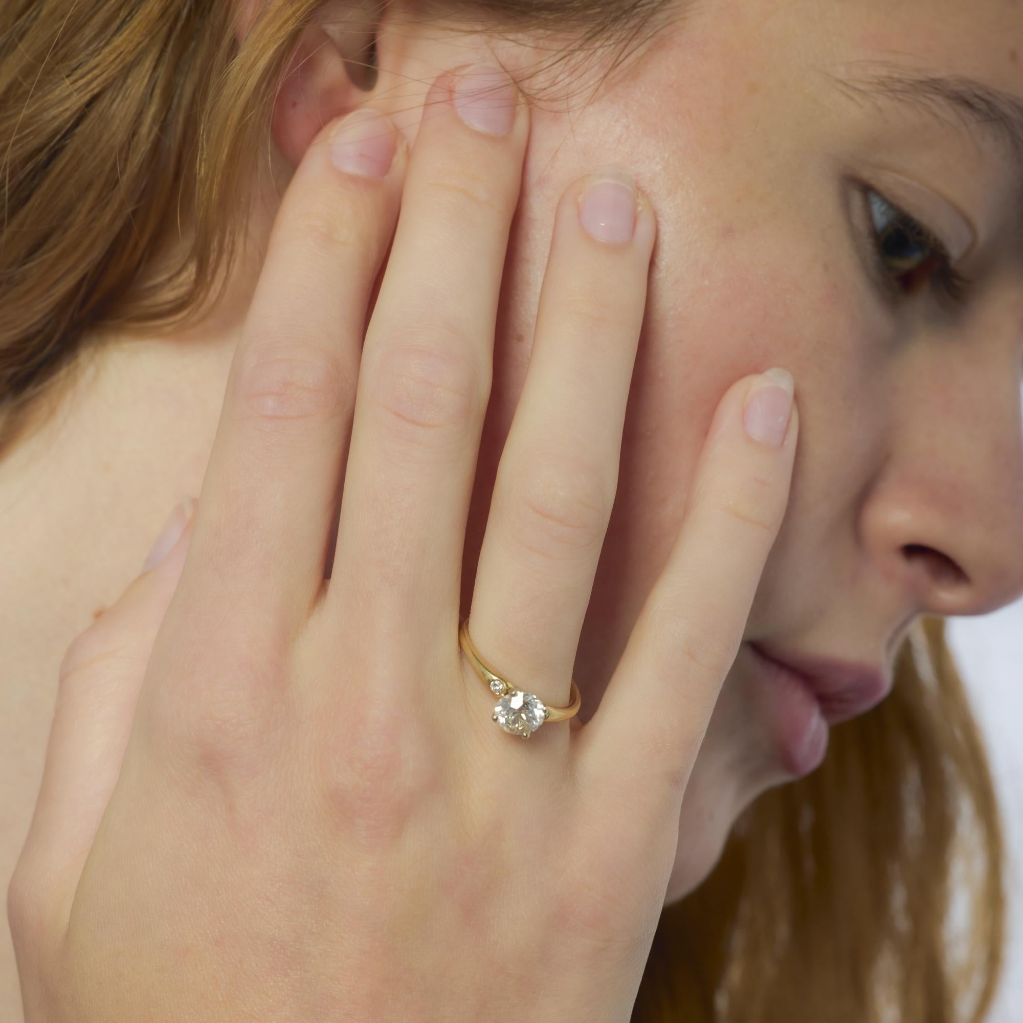 Este anillo bicolor, un diseño clásico de mediados de siglo, exhibe un diamante de talla europea antigua de 1,37 quilates flanqueado por tallas de transición en elegante oro amarillo y blanco.