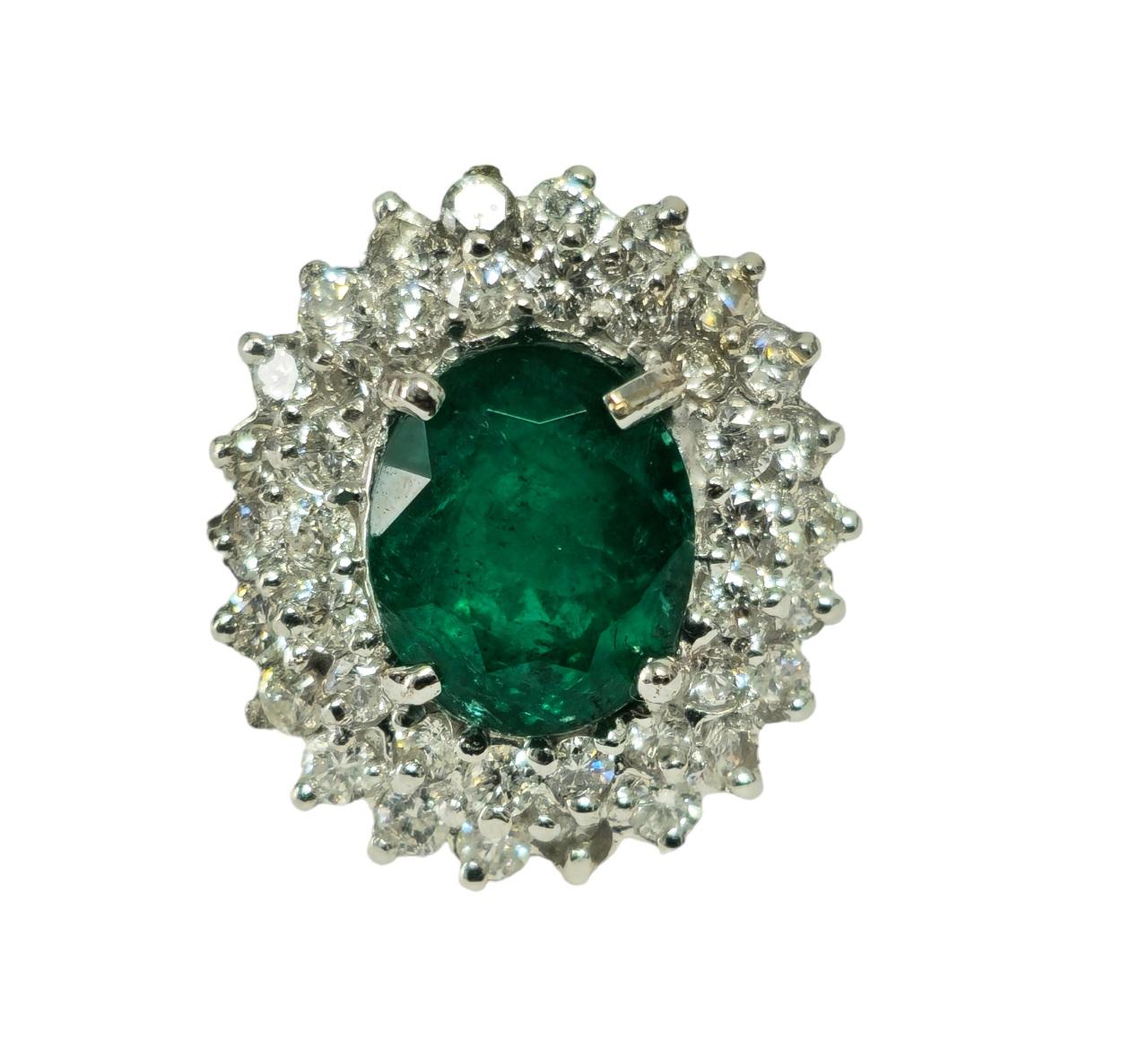 In luxurious 14k white gold, this exquisite cocktail ring features a stunning 3.05 carat oval-shaped emerald, displaying deep color and saturation, securely set in prongs. Encircling the emerald are 1.50 carats of round brilliant cut diamonds,