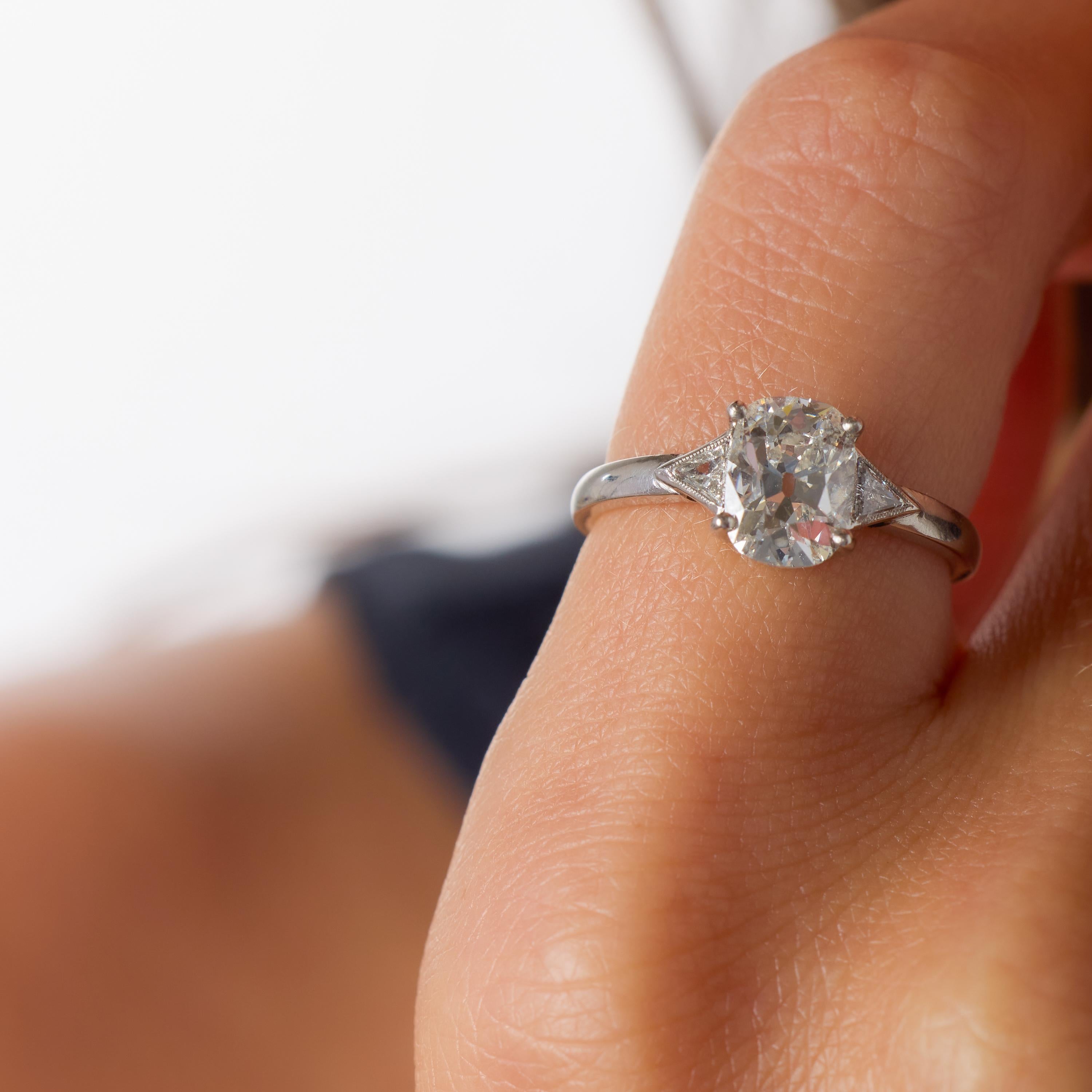 Cette bague de fiançailles moderne en platine met en valeur un diamant coussin de 1,52 carat de taille brillant, certifié par le GIA et rayonnant d'un éclat chaud et captivant. Sa forme gracieuse, ses arêtes douces et ses larges facettes lui