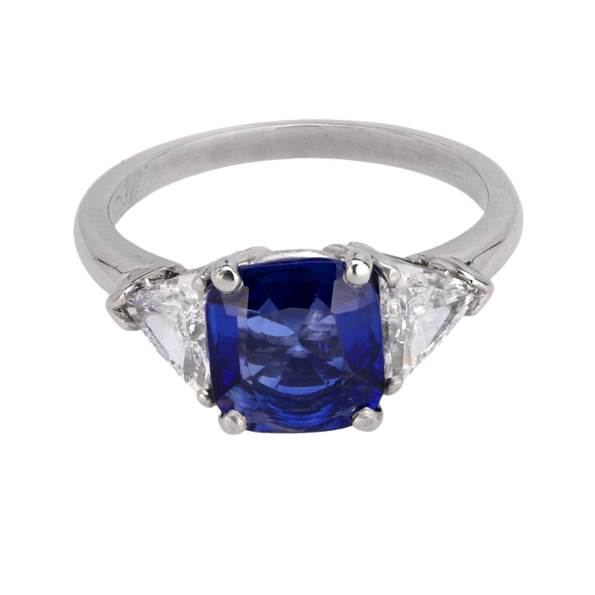 This modern platinum three-stone ring features a GIA-certified 1.55-carat cushion-cut blue sapphire from Madagascar, heated, accented by two trillion-cut diamonds totaling approximately 0.50 carats, F color, VS clarity. Circa 2020s.

Certificate: