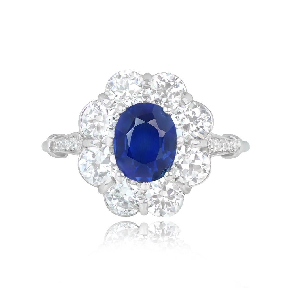 A cluster engagement ring with a GIA-certified 1.56-carat oval-cut natural sapphire at its center. It's surrounded by a halo of old European cut diamonds totaling 2.00 carats. Additional diamonds, approximately 0.08 carats in weight, are set along