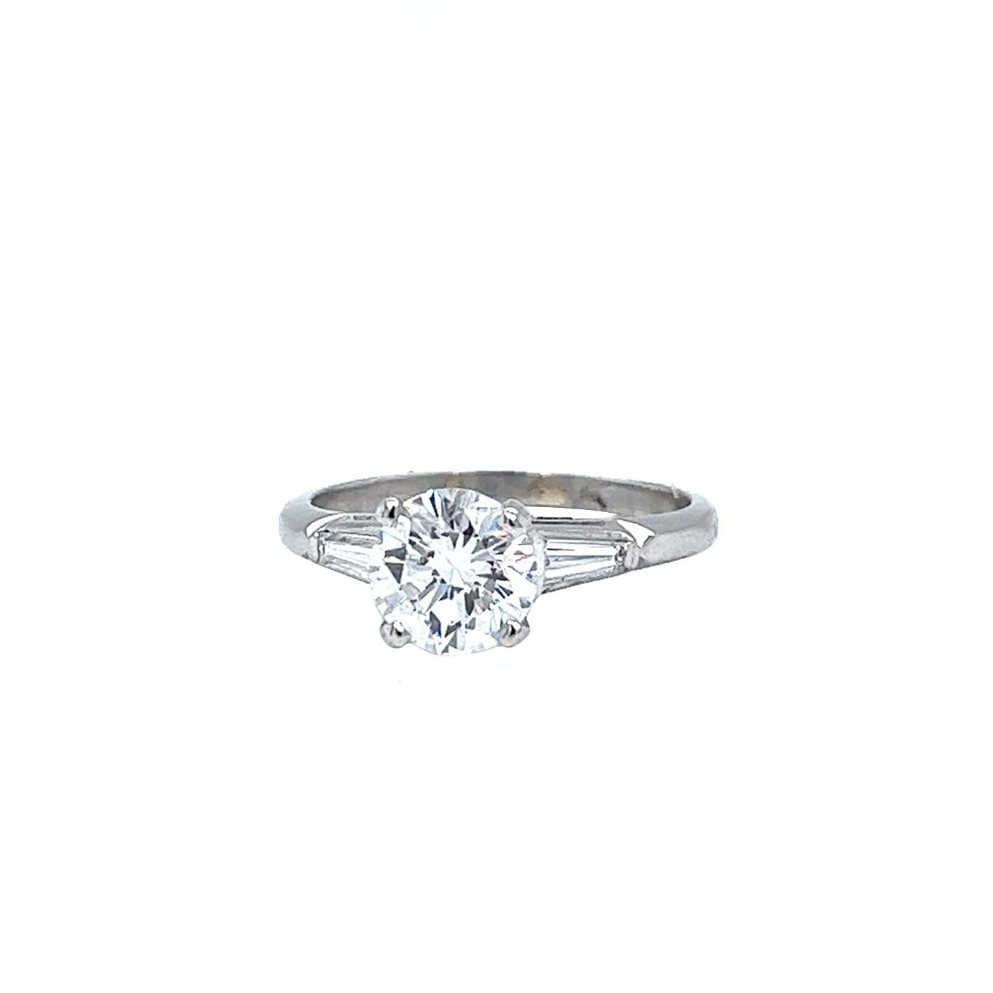 A Lovely Charming Natural Diamond Engagement Ring Showcasing a 1.64 Carat Round Brilliant Cut Diamond, E Color, and VS1 in Clarity with 0.45ct Side Baguettes Diamonds Features F Color, and VS1 Clarity, Finely Made with 14K White Gold. Size 6.5 Is