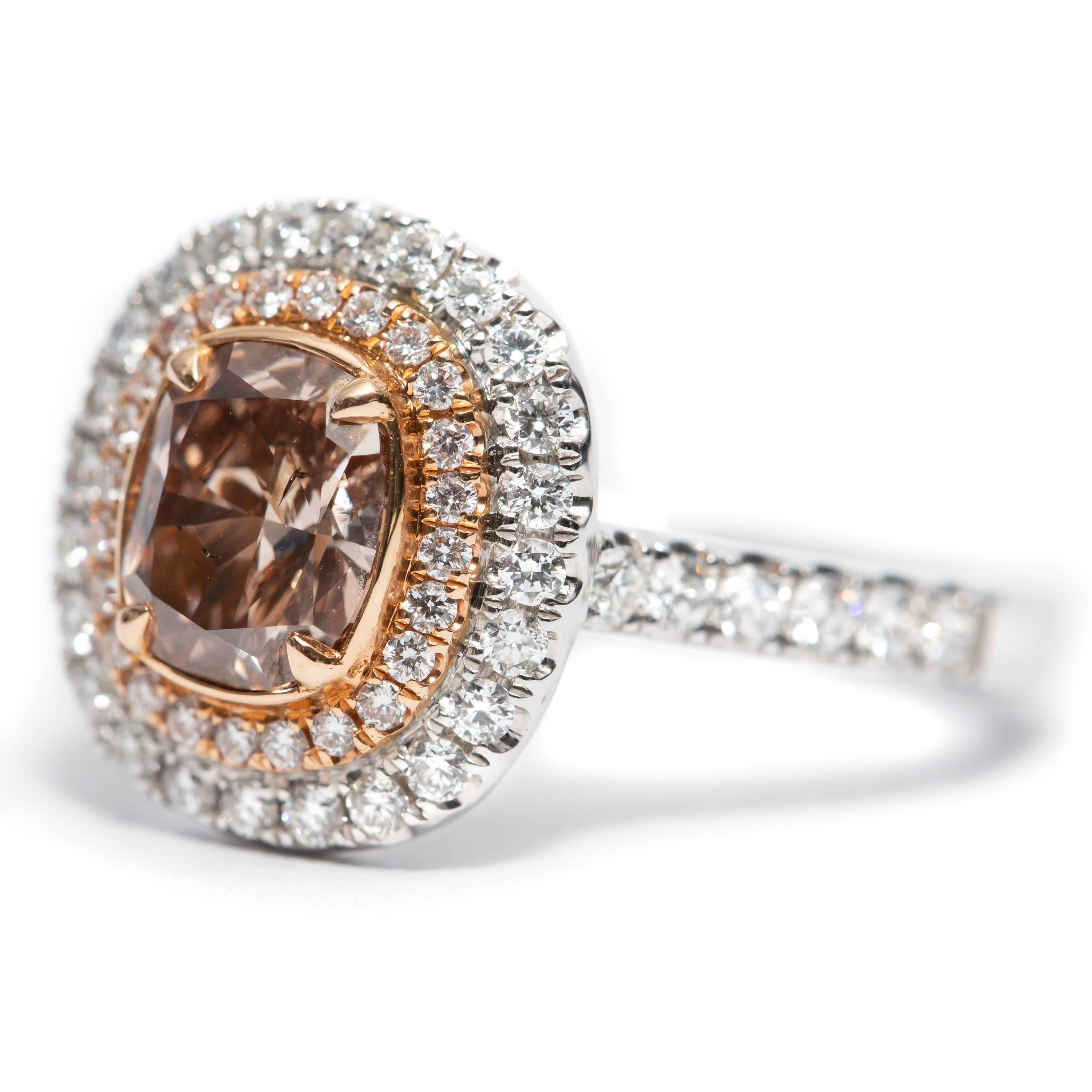 This Stunning GIA Certified 1.02 Carat Fancy Orange Brown Clarity SI2 Cushion Cut Diamond Engagement Ring features 0.63 Carat of Round White Brilliant Diamonds in a double halo and flowing down the shoulders set in 18 Karat White Gold. UK size M,