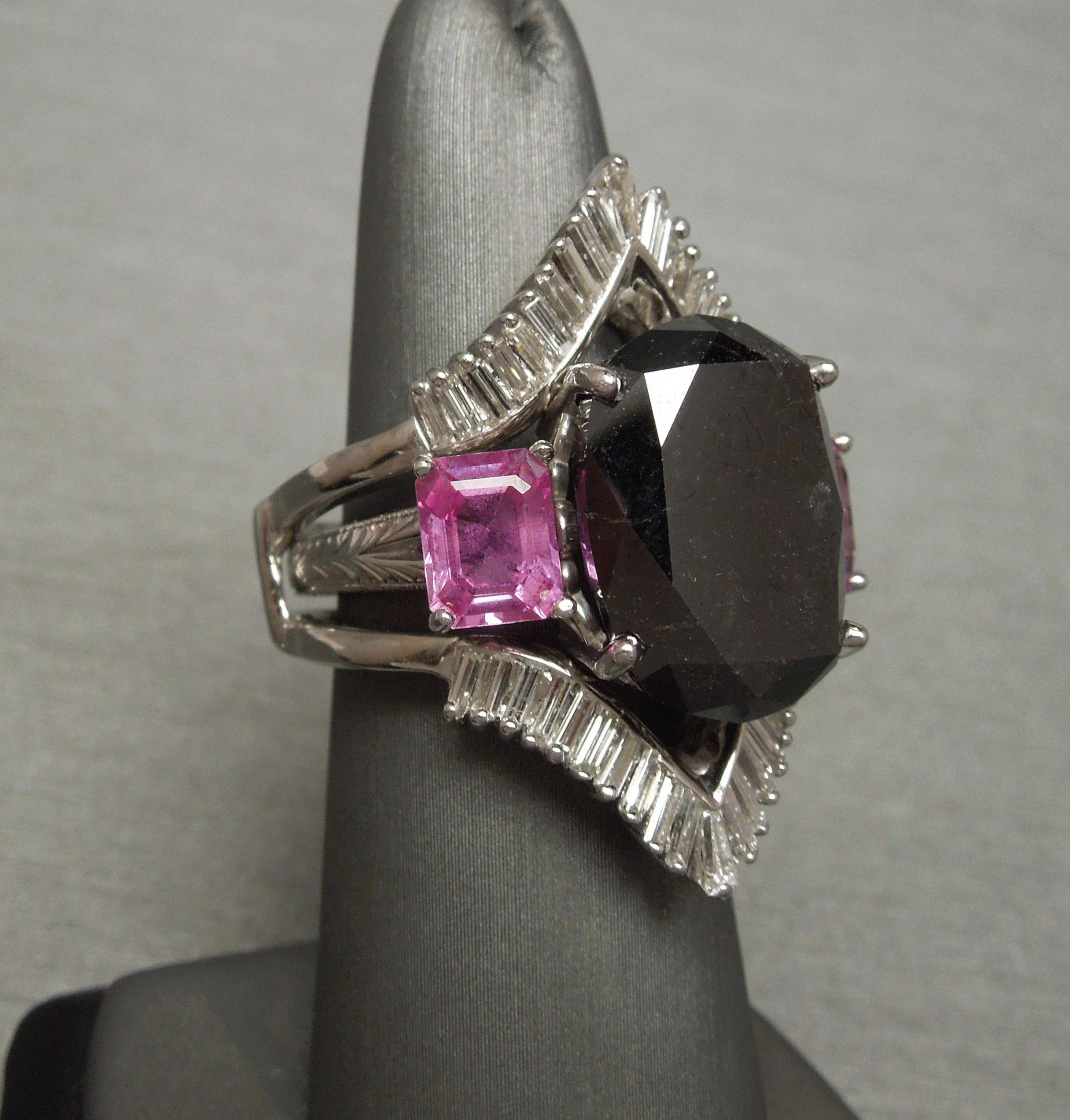 Nous sommes ravis de vous proposer cette bague à diamant noir et saphir rose de notre collection Beverly Hills Estate, qui présente un diamant noir central certifié GIA de 17,80 carats de taille ovale, solidement serti dans une monture à quatre