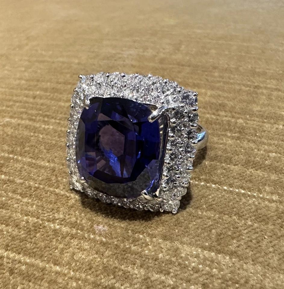 GIA 19.97 carat Cushion Tanzanite Ring with Diamond Halo in Platinum

Tanzanite and Diamond Ring features a lively 19.97 carat Natural Cushion cut Tanzanite with a Bluish Violet color surrounded with Natural Round Brilliant Diamonds, all set in