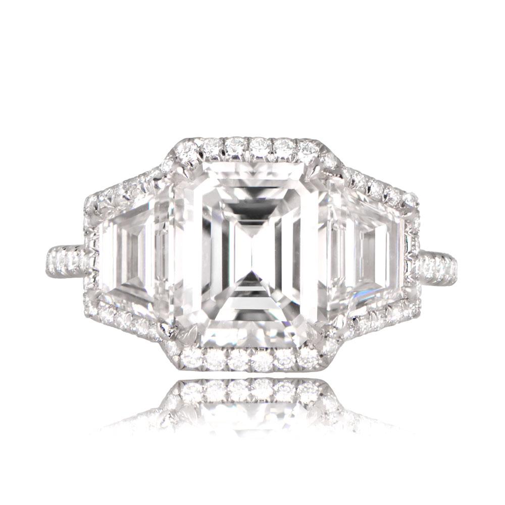 A stunning three-stone ring features a lively GIA-certified 2.03-carat emerald-cut diamond at the center, with exceptional D color and VS1 clarity. Flanking the center stone are two GIA-certified Trillian-cut diamonds. This exquisite ring is