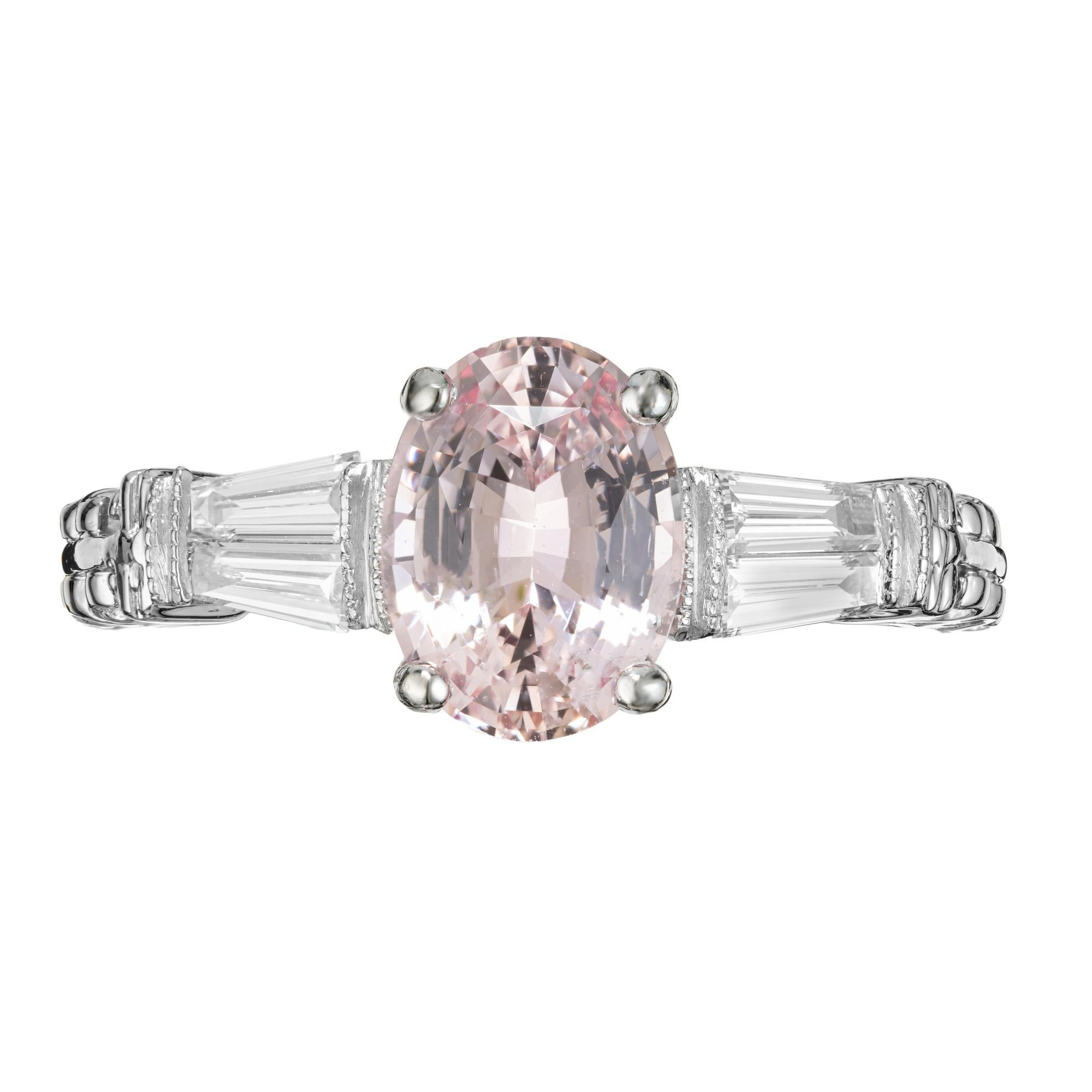 Pink Padparadscha Sapphire diamond engagement ring. GIA certified 2.07ct oval pink sapphire mounted in a platinum setting with 2 tapered baguette accent diamonds on each side. The shoulders of the setting are a very detailed with a carved scroll