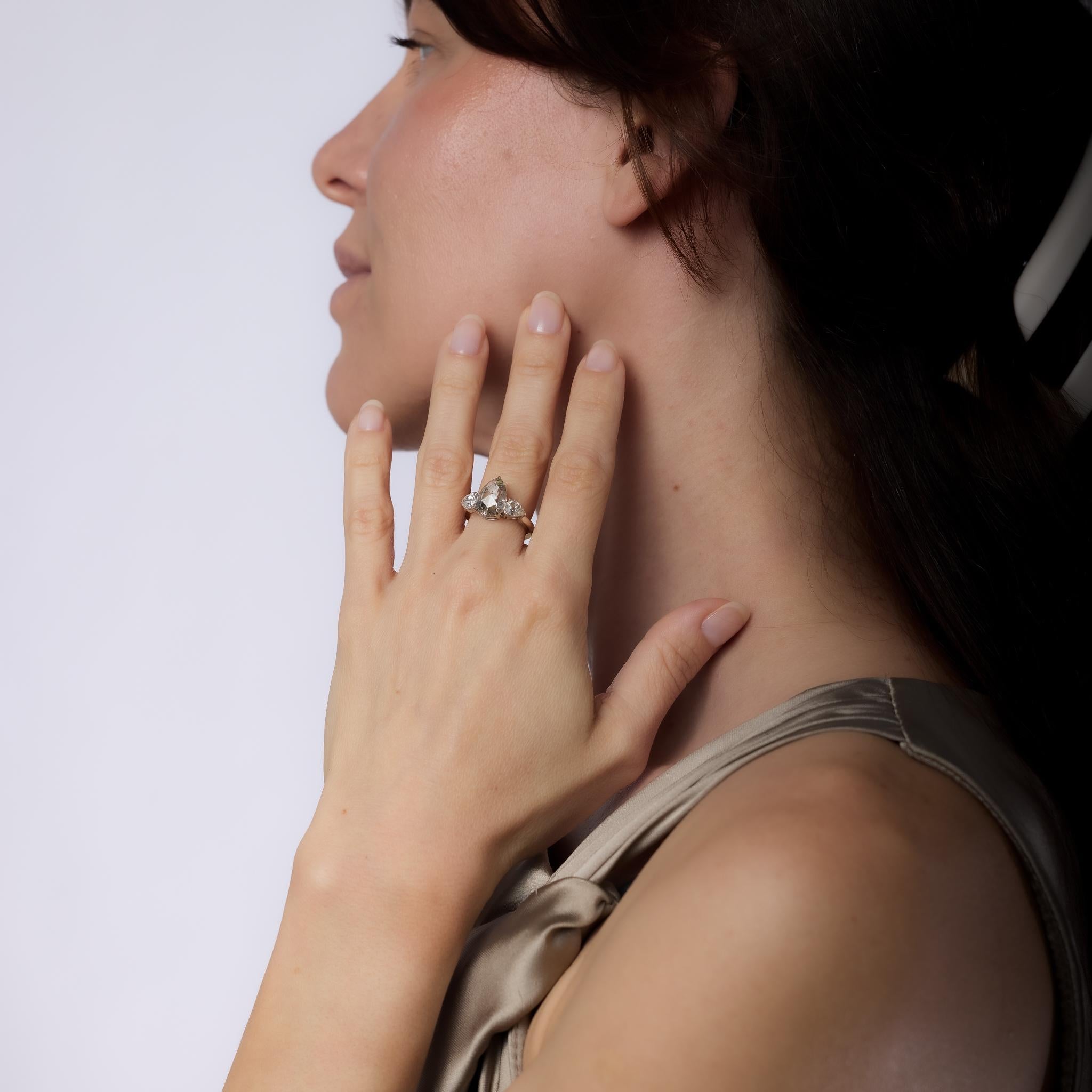 This mid-century platinum three-stone engagement ring features a GIA-certified 2.98-carat pear-shaped rose cut diamond, N color, very light brown, SI2 clarity, flanked by two pear-shaped old mine cut diamonds totaling approximately 1.10 carats, H
