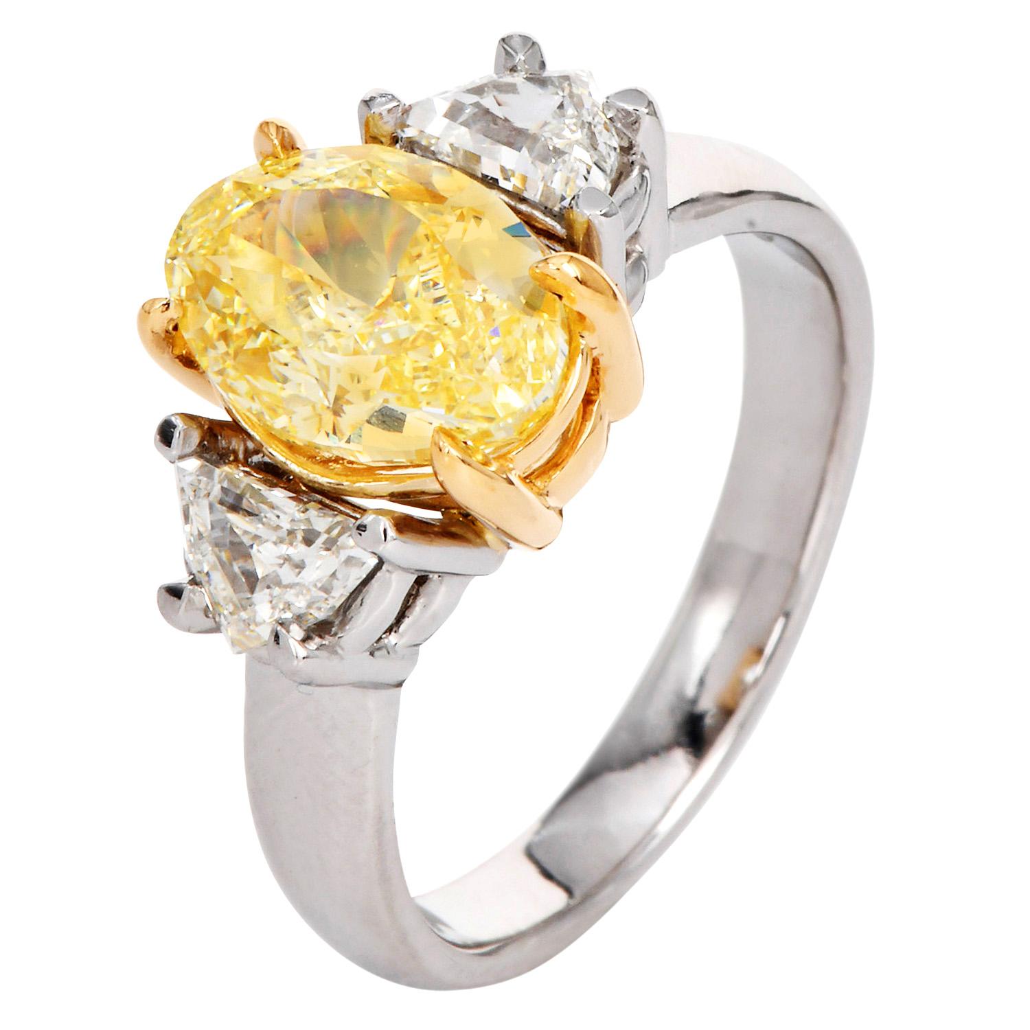 Questo squisito anello di fidanzamento a tre pietre mette in mostra un vibrante diamante ovale Fancy Yellow da 3,02 carati, apprezzato per il suo ricco e forte colore giallo, il colore uniformemente distribuito e l'eccezionale purezza VVS2. La