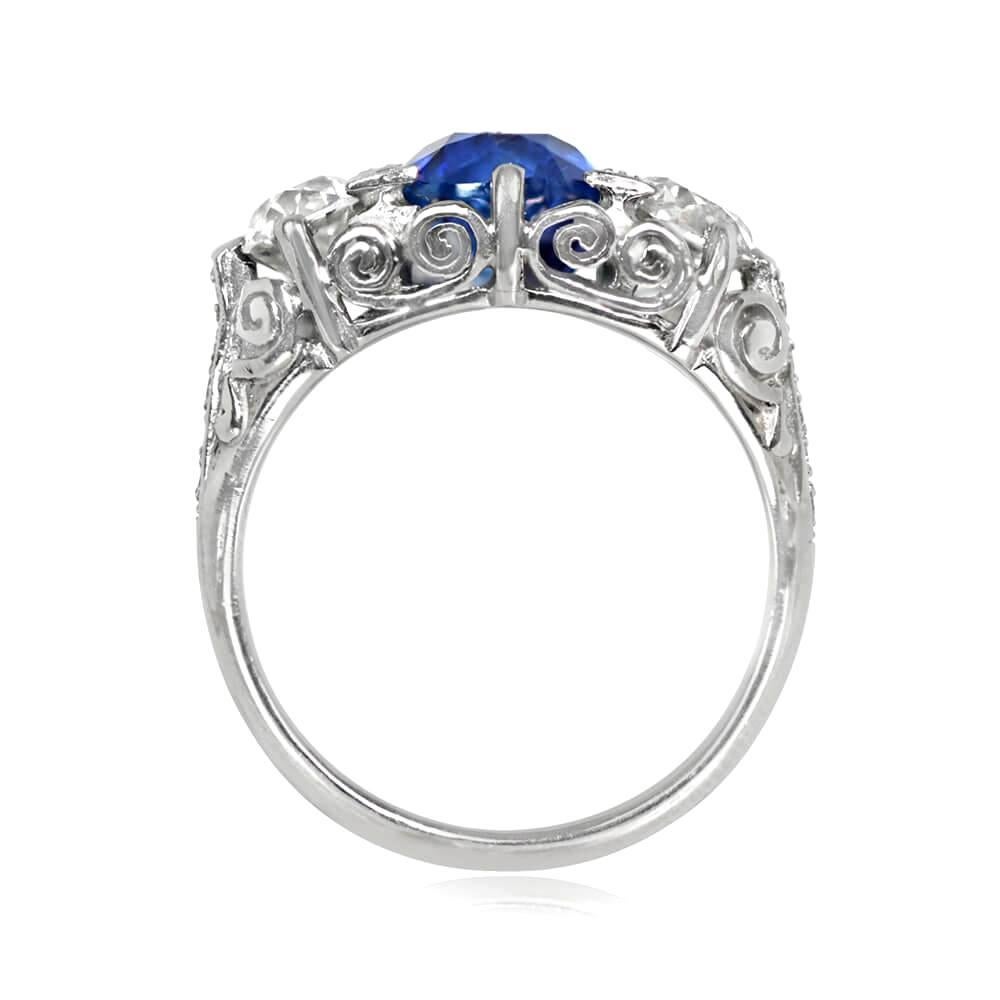 This stunning Art Deco-style engagement ring features a breathtaking 3.06 carat cushion cut sapphire, securely held in place by triangular prongs adorned with single-cut diamonds. The center stone is flanked by two beautiful H color and VS2 clarity