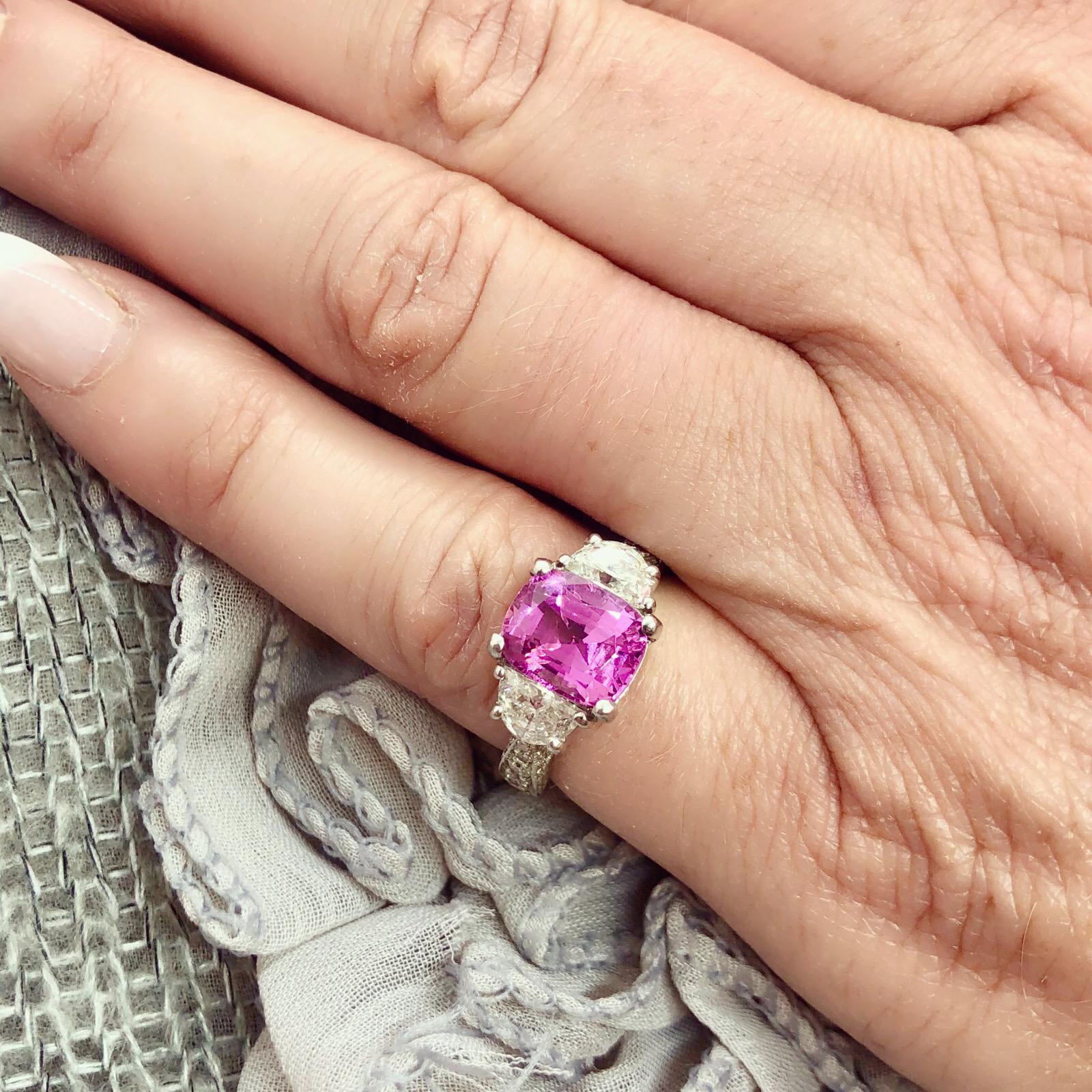 Eye-catching estate ring features one extraordinary 3.34ct rectangular cushion cut purplish pink sapphire with exceptional light return and saturation of color, and 52 half moon & round diamonds with a total approximate weight of 1.24cts in a