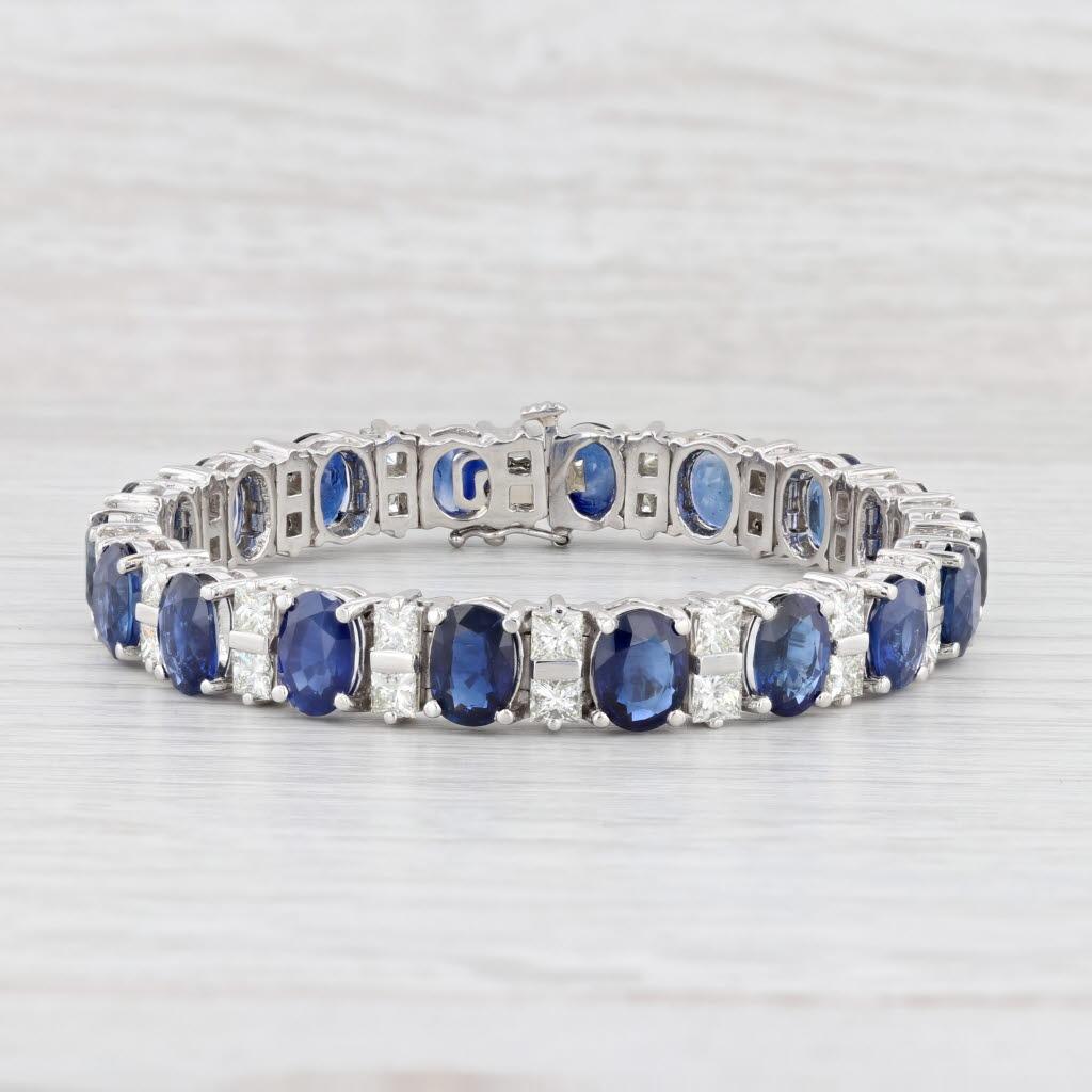 This stunning custom bracelet is set with deep blue oval sapphires accented by VS2 princess diamonds, creating a lovely white and blue contrast along a polished platinum chain. This statement piece displays the highest craftsmanship and comes with a