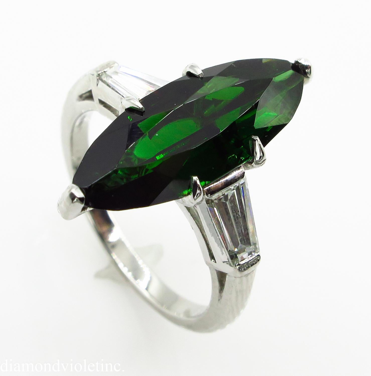 A Breathtaking Estate Vintage HANDMADE Platinum (stamped) Engagement ring dazzles GIA certified 3.10ct Marquise Shaped NATURAL Green Tourmaline; with measurements of 18.43x7.14x3.83mm. GIA report # 6197324861.
It is set with 2 Step cut Tapered