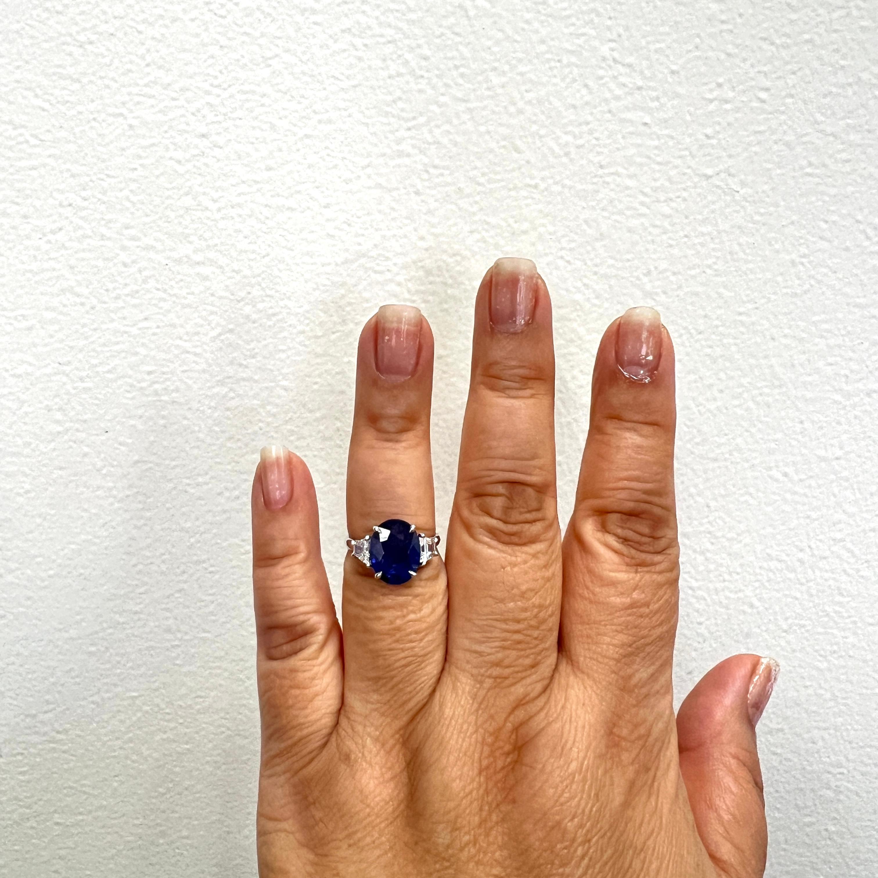 Precioso óvalo de zafiro azul de 4,48 quilates con trapecios de diamantes blancos de buena calidad de 0,95 quilates.  Hecho a mano en oro blanco de 18 quilates.  Anillo talla 6,5.  Certificado GIA incluido.