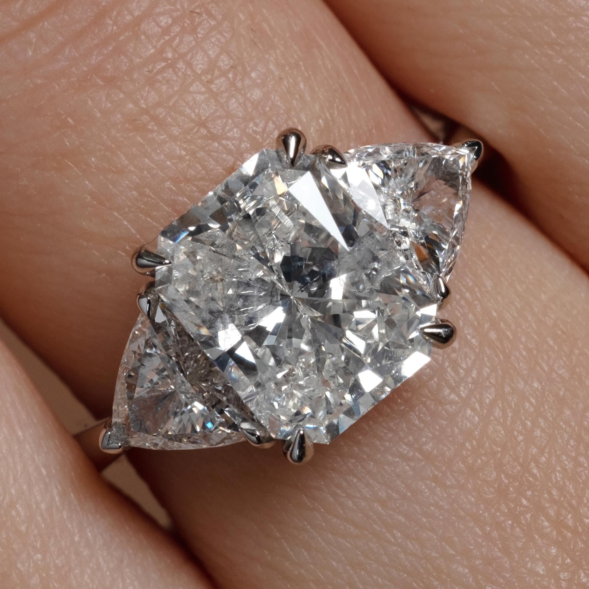 A Breathtaking Estate HANDMADE PLATINUM (stamped) Radiant Diamond Three-Stone Engagement ring. The Prong Set Radiant Diamond is 3.01ct; with measurements of 9.70x7.57x5.13mm. GIA Certified in J color I2 clarity (Near Colorless and eye clear). 
It is