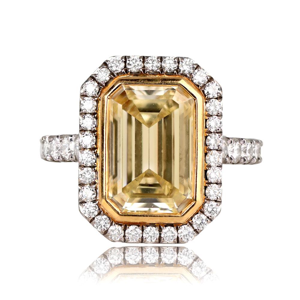 This striking fancy-colored diamond ring highlights a 4.04-carat fancy yellow emerald-cut diamond with VVS2 clarity. It is beautifully accented by prong-set round brilliant-cut diamonds encircling the center stone and adorning the shoulders. The