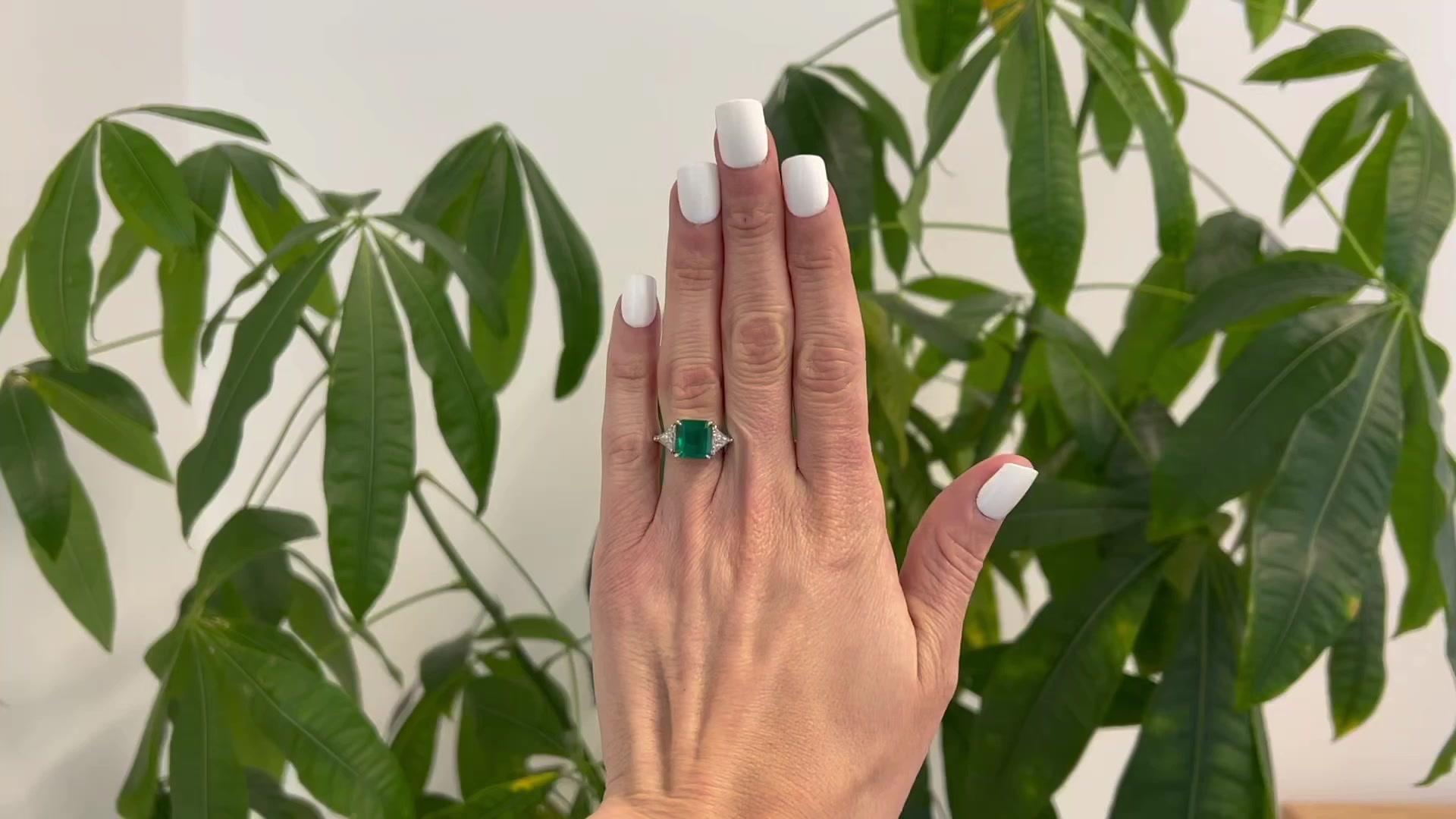 One GIA 4.10 Carats Colombian Emerald Diamond Three Stone Ring. Featuring one GIA octagonal step cut emerald of 4.10 carats, accompanied with GIA #2185721009 stating the emerald is of Colombian origin. Accented by two trillion cut diamonds with a