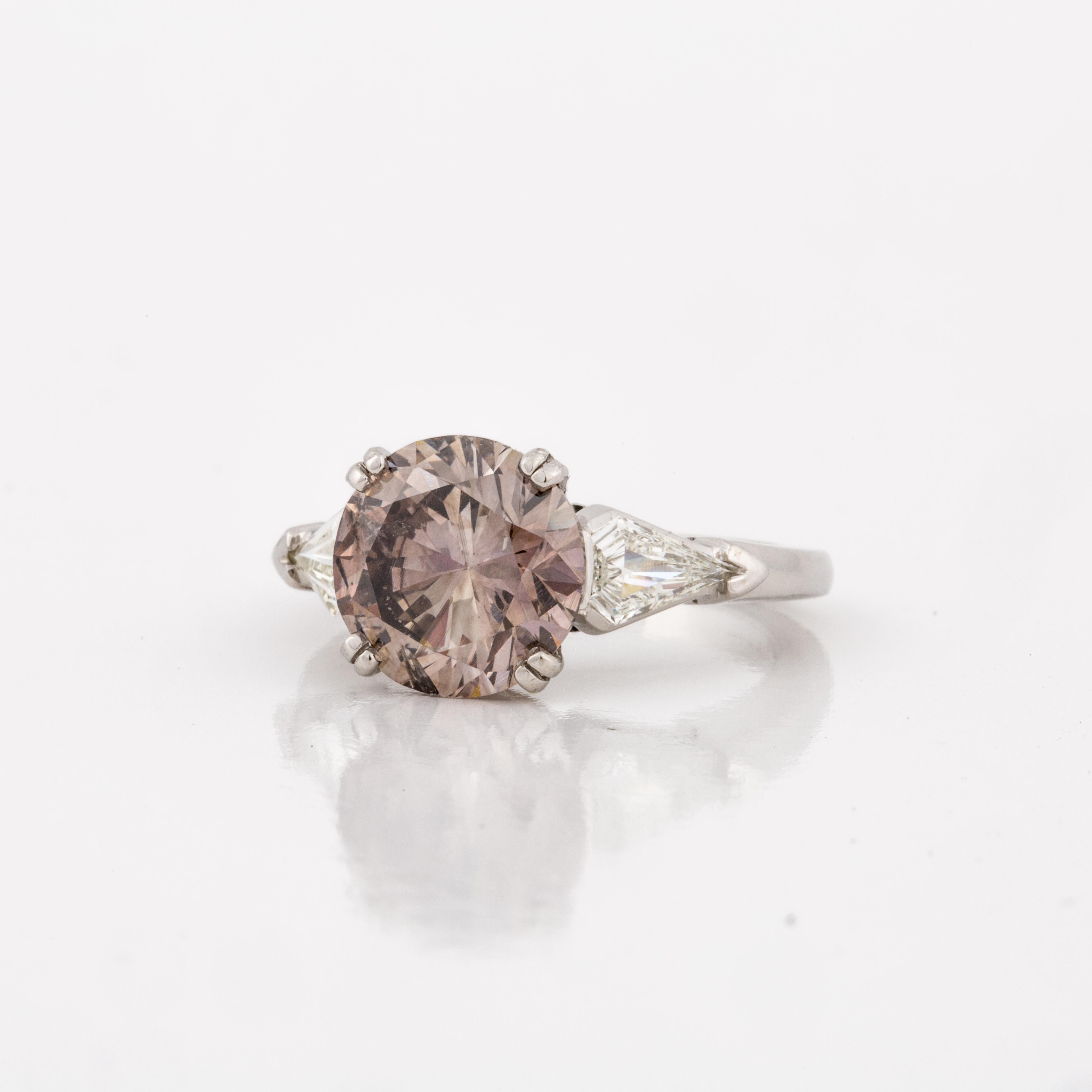 Platinum diamond ring featuring a 4.17 carat fancy dark pinkish-brown diamond accompanied by a GIA certificate.  There are 2 kite shaped accent side stones that total 0.60 carats, I-K color and VS2 clarity.  Ring is currently a size 6.  