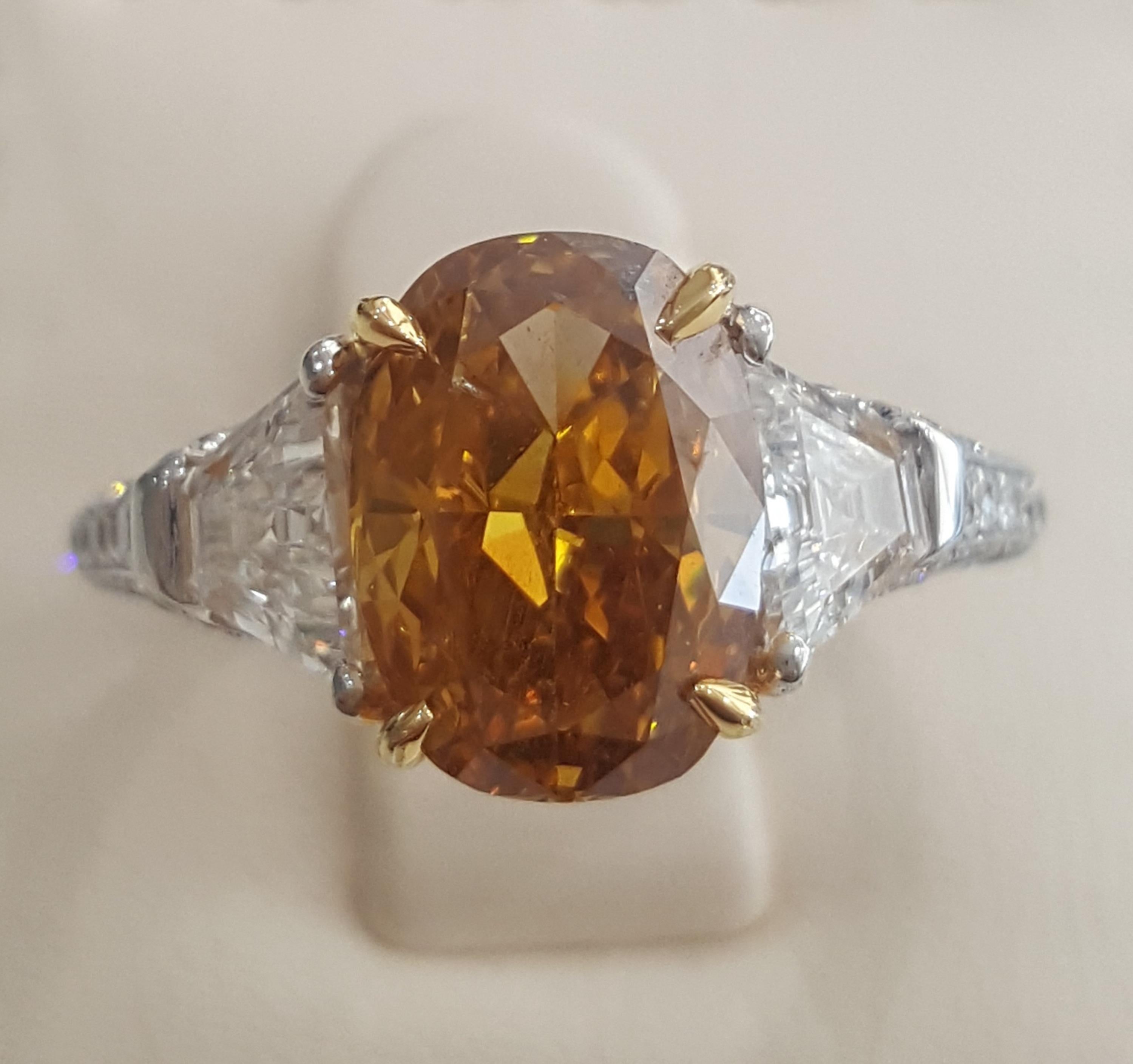 This bold, brilliant and exceptional ring is beautifully  designed and handmade by Moguldiam Inc. Centering a GIA certified natural fancy deep orange yellow oval brilliant weighing 3.09 carat flanked by two triangles and round brilliant diamonds