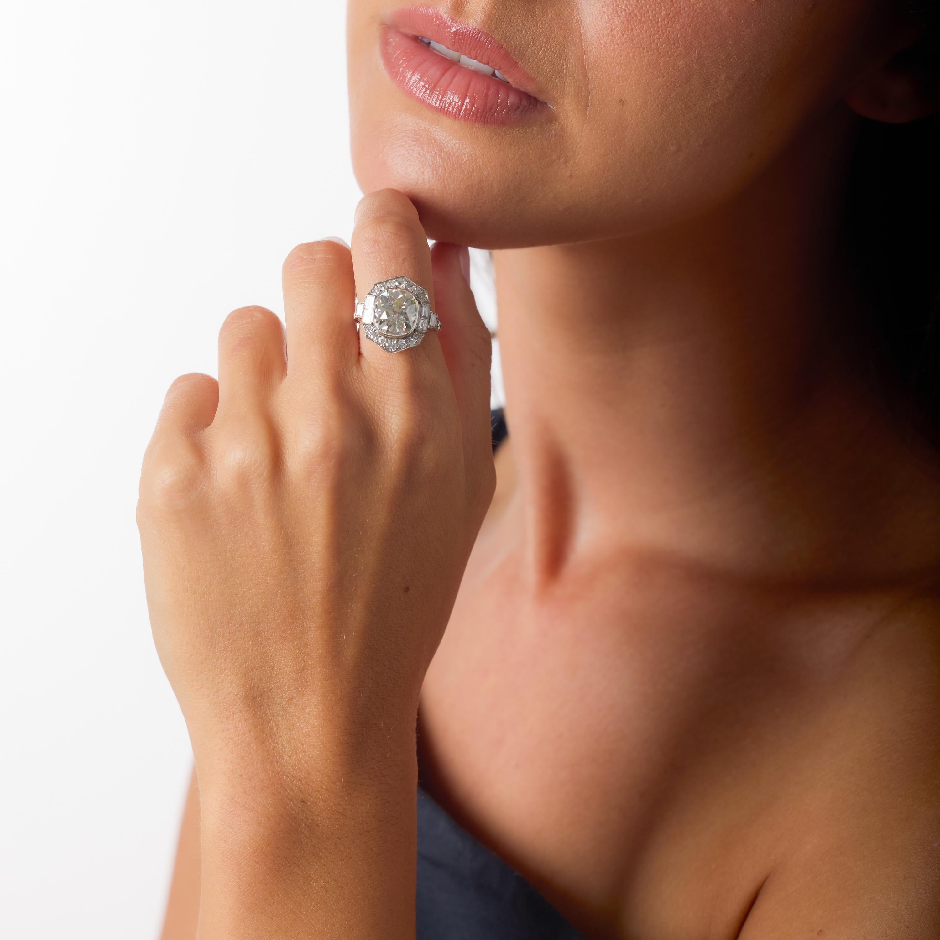 Im Mittelpunkt dieses außergewöhnlichen Platinrings steht ein bemerkenswerter 4,43-Karat-Diamant im Old-Mine-Schliff - ein beeindruckender Stein, dessen antike Facettierung und großzügige Proportionen einen Glanz erzeugen, der mit keinem modernen