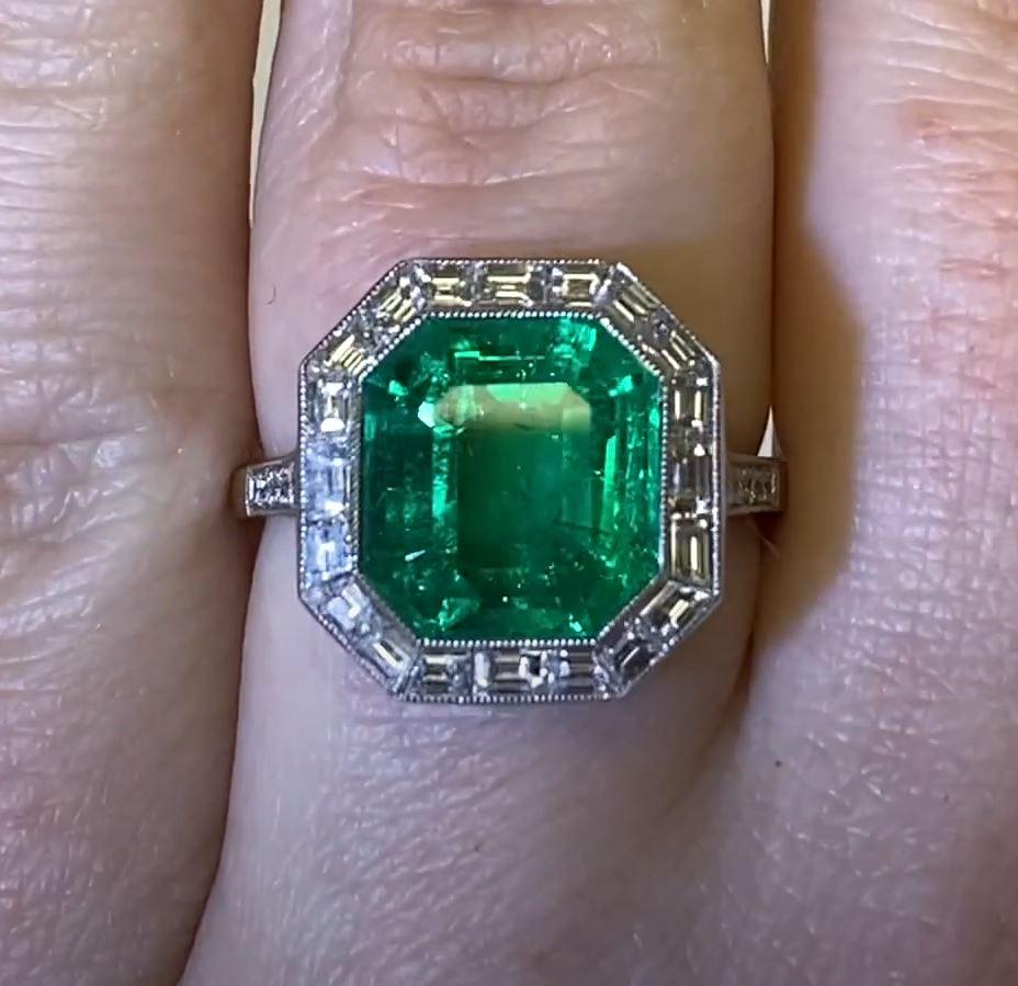 Featuring a GIA-certified 4.55ct emerald-cut Columbian emerald with minor oil treatment, this engagement ring is a true standout. Set in platinum, the emerald sits within a bezel and is surrounded by a halo of baguette cut diamonds weighing 0.77ct