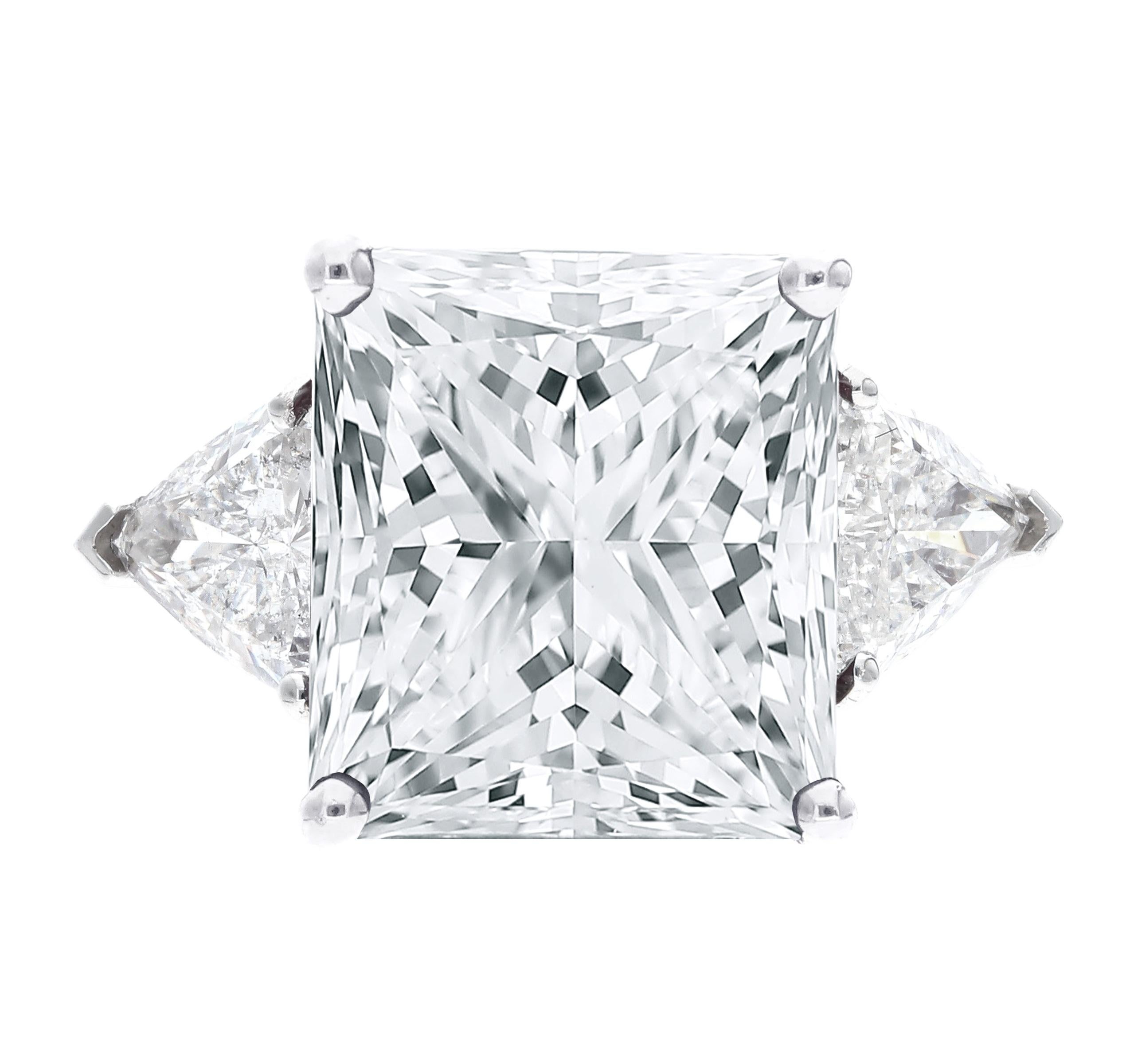 This stunning ring features a GIA certified 5.01 carat princess cut diamond, set in an 18K white gold band adorned with trillion diamonds on side. 
The center diamond has a color grade of H and a clarity grade of VVS1, ensuring impressive quality