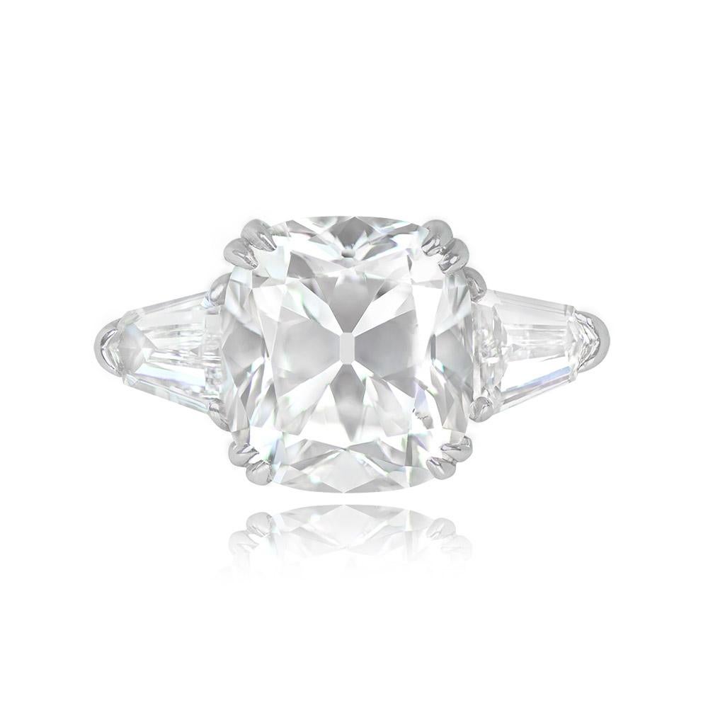This elegant engagement ring showcases an antique cushion-cut diamond in a prong setting. The centerpiece is a GIA-certified 5.01-carat diamond with a G color grade and VS2 clarity. Complementing the central stone, two bullet-cut diamonds, each
