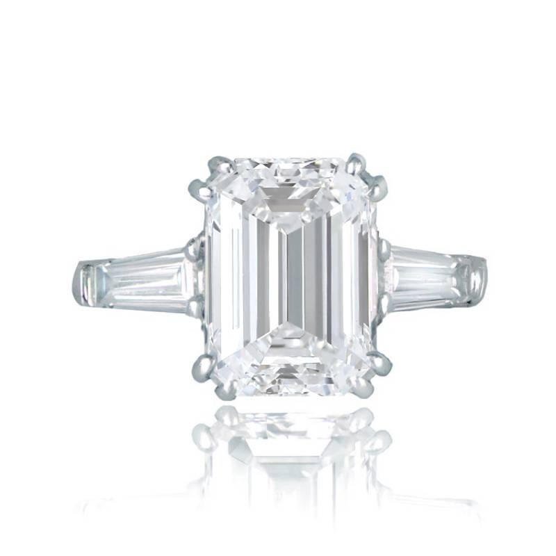 This impressive solitaire ring showcases a GIA-certified 5.01 carat Emerald cut diamond with G color and VS1 clarity. Complementing the center diamond are two tapered baguettes. Meticulously handcrafted in platinum, this ring offers a low-profile