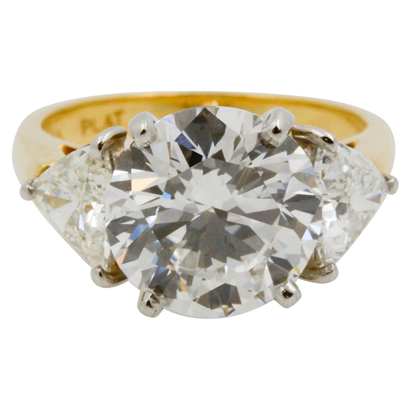 Showcasing a GIA certified 5.02 ct round brilliant cut diamond with D color and VVS2 clarity, this ring is paired with two trillion side diamonds, weighing a total of 1.55 carats with D-E color and SI1 clarity. The diamonds are on an 18k yellow gold