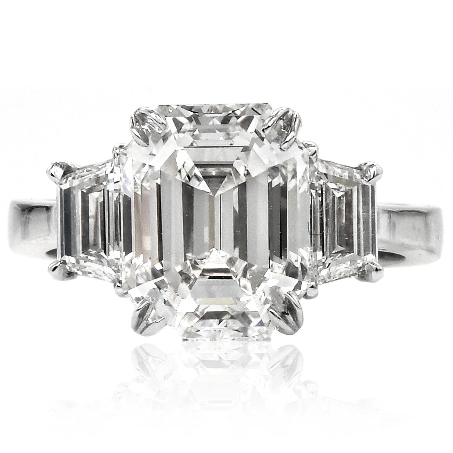 This exquisite diamond engagement ring is handcrafted in platinum. The center showcases one emerald cut diamond weighing 4.57 carats, graded I color, and VVS2 clarity. Shoulders are set with one diamond trapezoid graded H-I  color, VS clarity