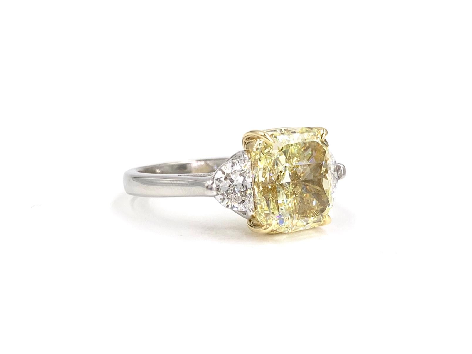 A simply stunning platinum and 18 karat yellow gold three stone ring featuring a vibrant 5.55 carat GIA certified fancy light yellow round-cornered rectangular modified brilliant diamond, VS2 clarity, No fluorescence. Diamond is perfectly flanked by