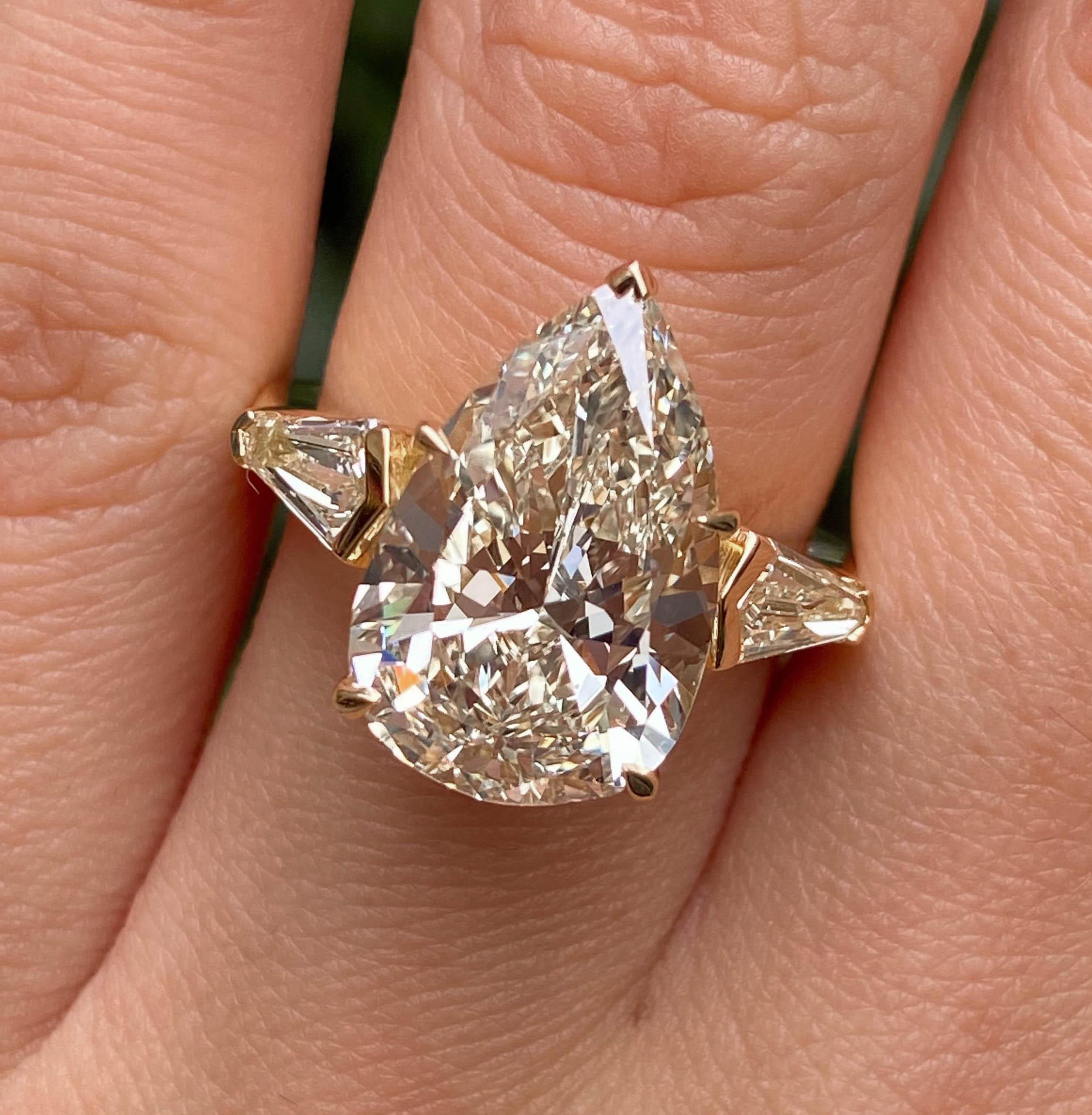 A Breathtaking Estate Vintage HANDMADE Three-stone 18k Yellow Gold (stamped) Engagement ring dazzles GIA certified 4.92ct Pear Shaped Diamond center diamond in O-P color and VS2 clarity; with measurements of 15.35x9.82x5.67mm. GIA report #
