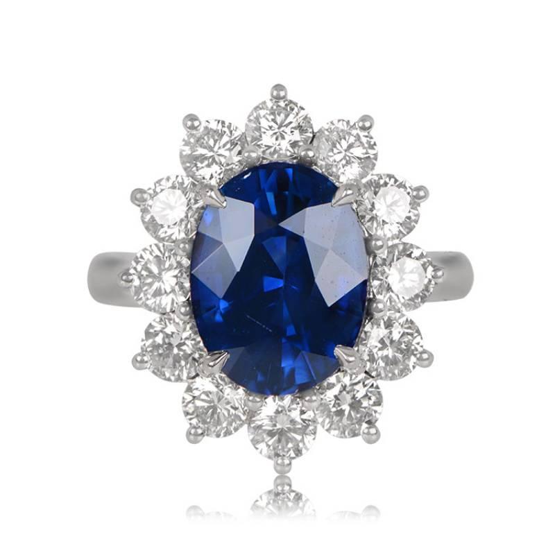 An exquisite cluster ring showcases a 5.99-carat natural oval sapphire at its center, surrounded by a cluster of brilliant-cut diamonds weighing a total of 2.06 carats. This hand-crafted platinum ring boasts a low-profile design. Notably, the center