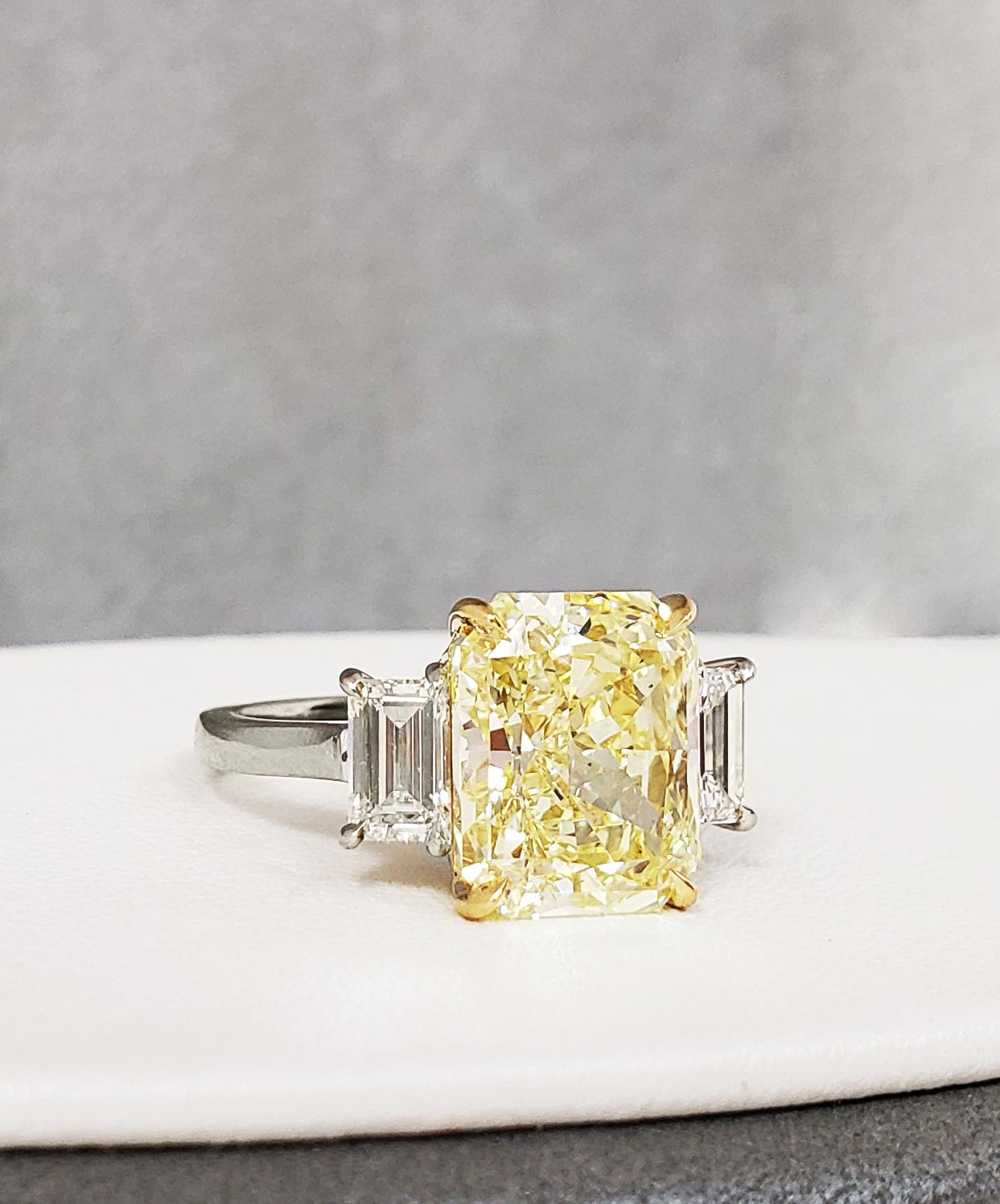 The clarity in this center Fancy Yellow radiant diamond is VS2 it is flanked by a pair of matching emerald cut white diamonds 1.10 total carat weight for a modern and tailored look. The center stone is certified by GIA #220513527 (see picture for