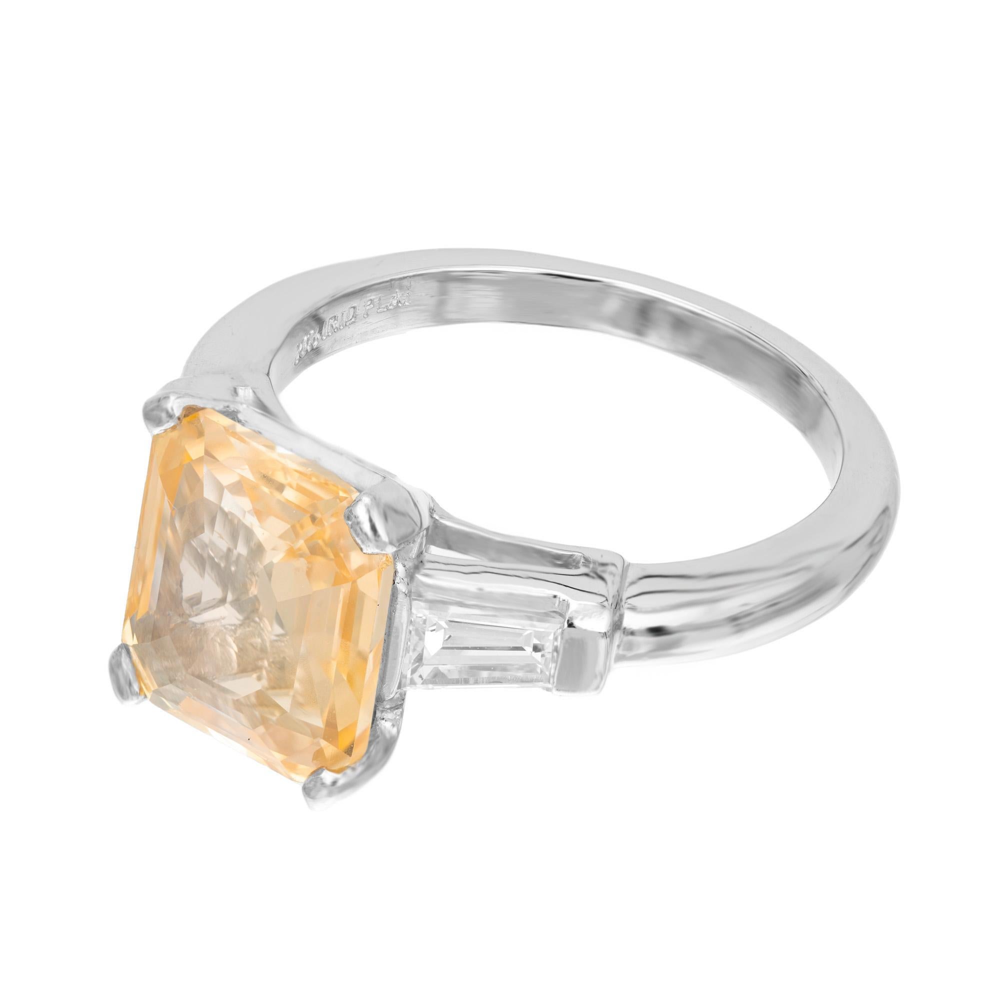 Spectacular sapphire and diamond Art Deco three stone engagement ring. The center stone is a octagonal emerald step cut orange and yellowish 6.04ct sapphire. Mounted in a platinum setting and accented with 2 tapered baguette side diamonds. The GIA