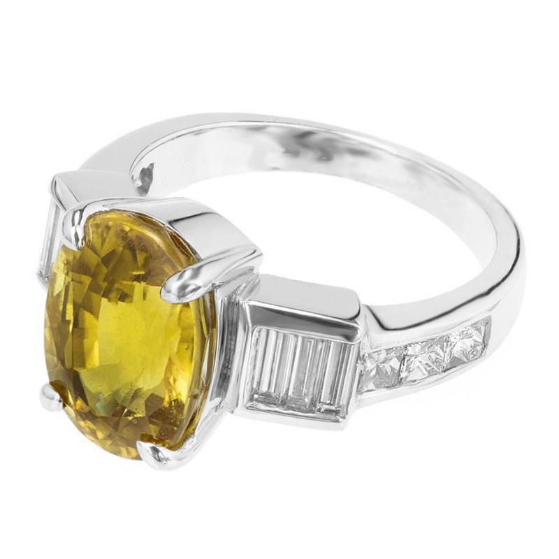 1970's bright but warm, yellow sapphire and diamond engagement ring. GIA certified natural, no hear oval brilliant cut yellow sapphire, centered in a platinum setting accented with six straight cut baguette and six princess cut diamonds on both