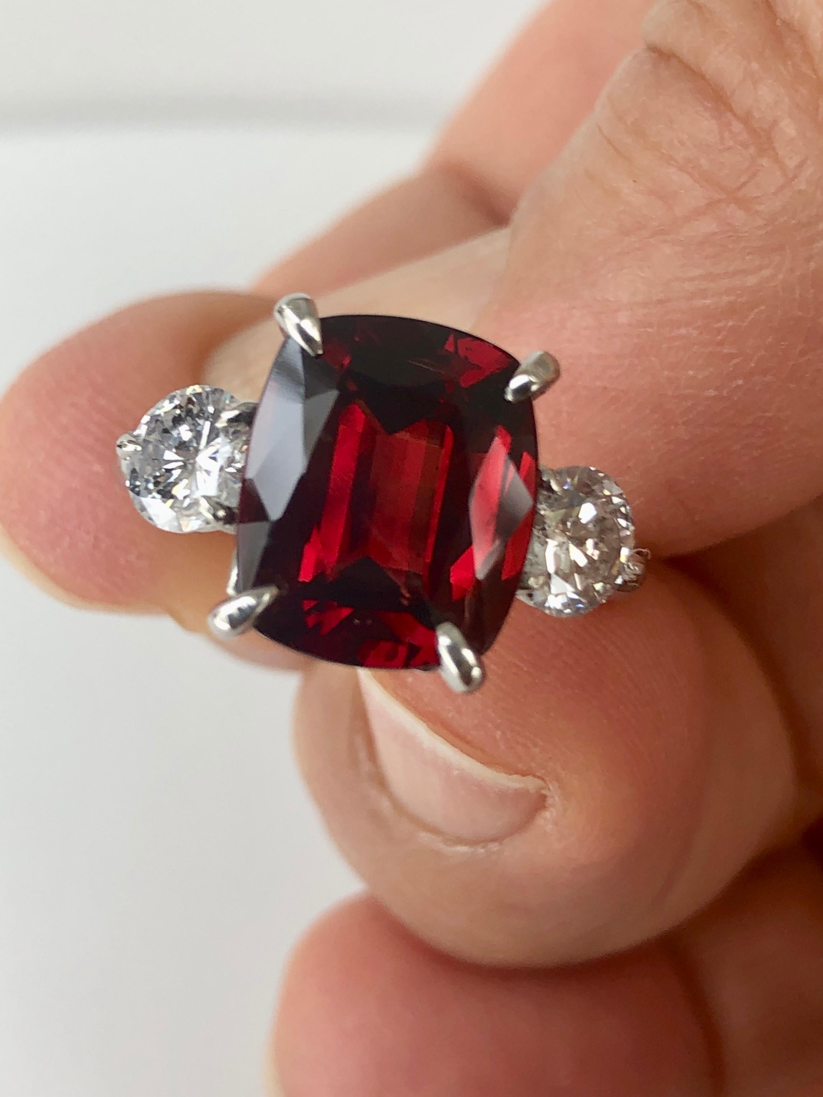 Fine unheated GIA-certified natural Burma red spinel and diamond engagement three-stone ring in platinum. The cushion-cut natural Burmese red spinel weighs a total of 5.16 carats and two round brilliant cut diamonds weigh a total of 1.10 carats, G
