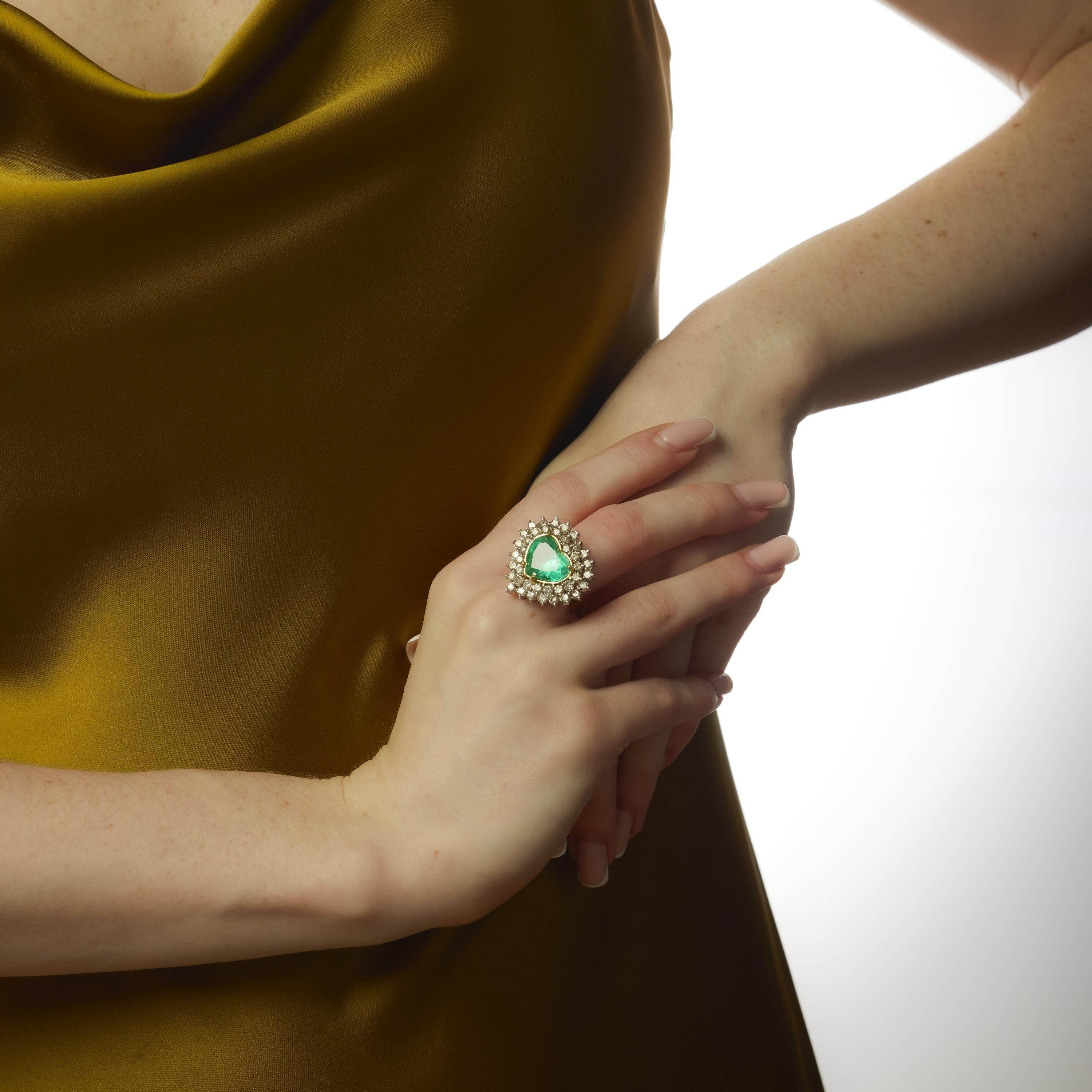 Cette bague vintage des années 1980 est centrée sur une époustouflante émeraude colombienne en forme de cœur de 6,80 carats, certifiée par le GIA (#2231603558) et traitée de manière minimale (F1) pour préserver sa beauté naturelle. Encadré par