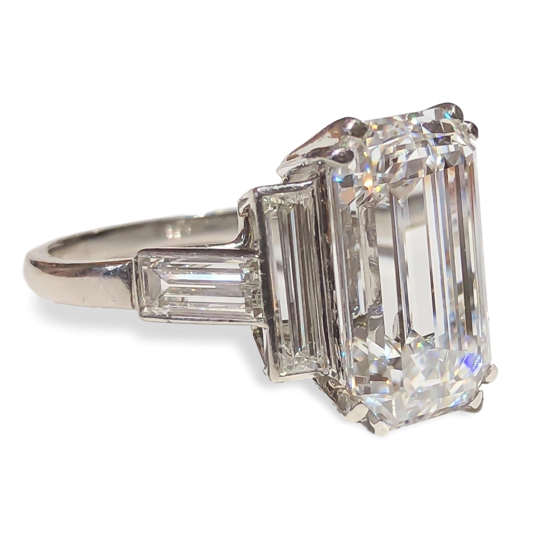This exquisite diamond is set in an English art deco 1920's platinum Cartier setting with complementing emerald cut diamonds. Timeless and classic design, the center is set in double prongs and flanked by four (4) bezel set emerald cut diamonds. The